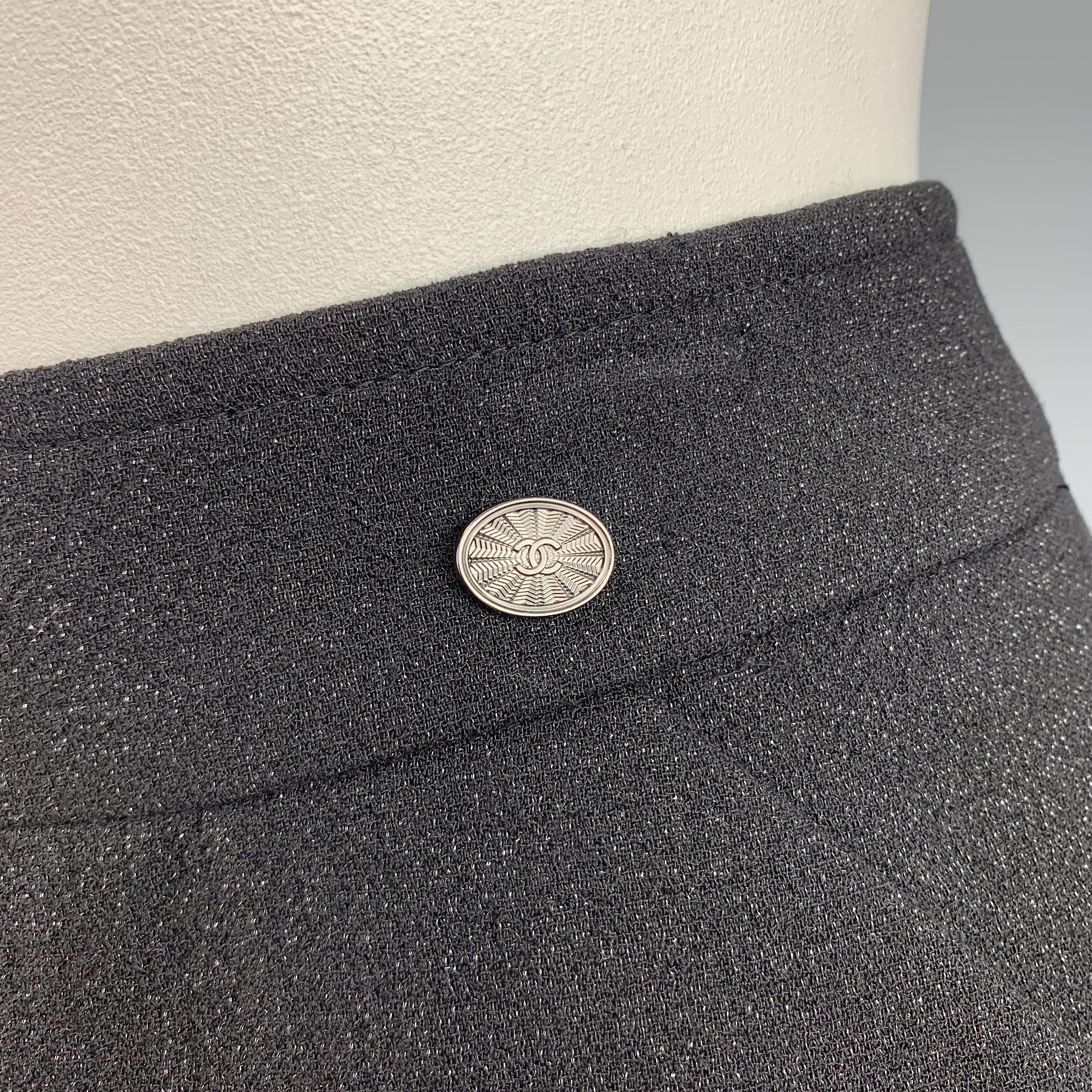 CHANEL pencil skirt comes in a black wool crepe with silver tone sparkle texture throughout slanted pockets, and a silver tone CC emblem at waist. Made in France.

Excellent Pre-Owned Condition. Retail: $1,600.00.
Marked: FR 50

Measurements:
Waist: