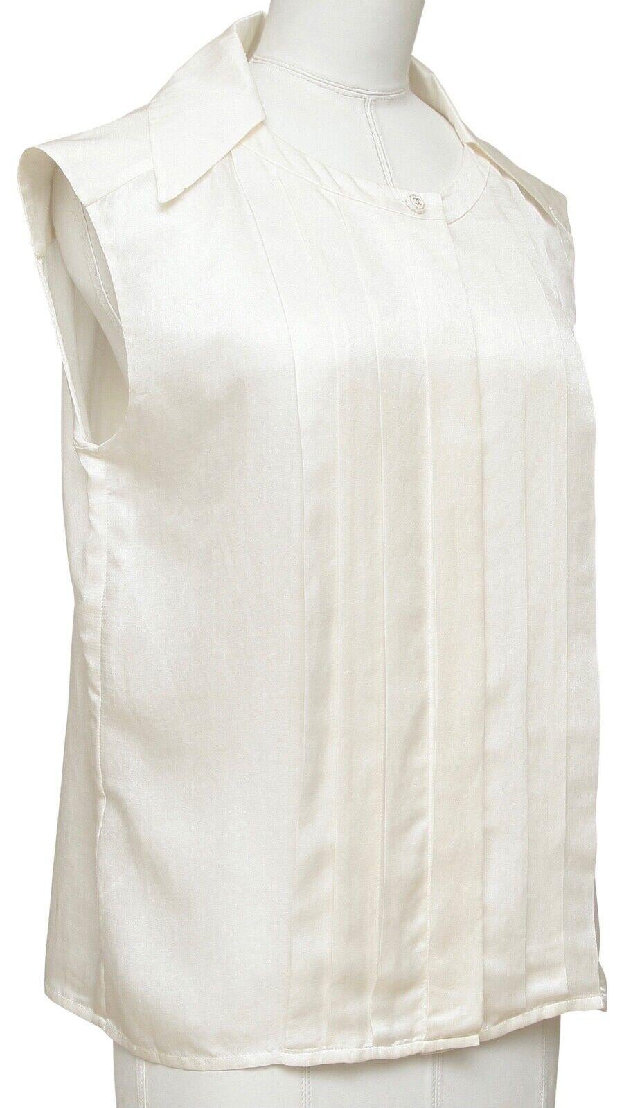 GUARANTEED AUTHENTIC CHANEL SLEEVELESS IVORY BUTTON DOWN SHIRT

Design:
 - Sleeveless lightweight ivory top.
 - CC button at neckline, remainder of buttons covered down front.
 - Vertical pleats front and back.
 - Pointed collar.

Material: 63%