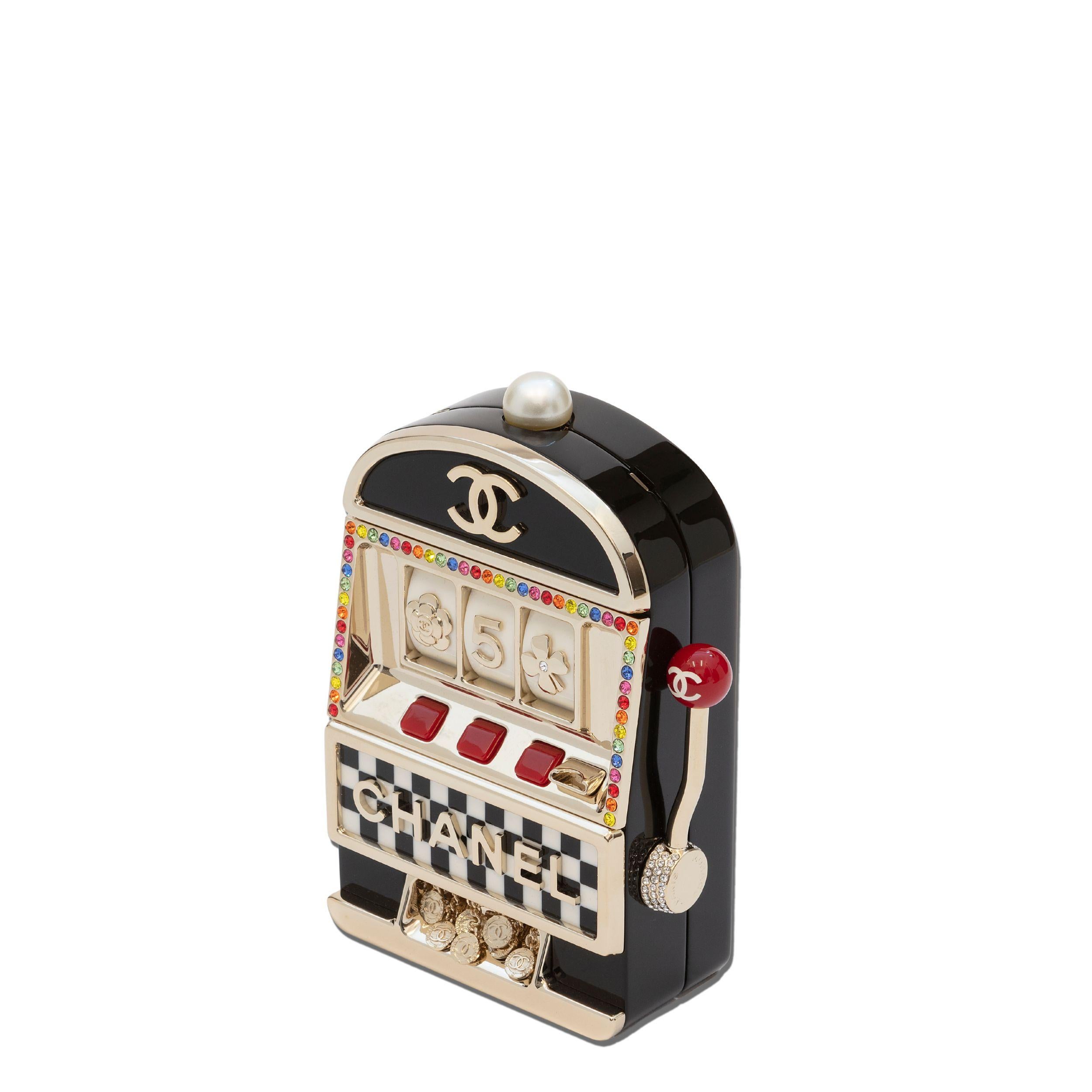 La pochette da sera Casino Minaudière di Chanel è un pezzo esclusivo e molto ricercato della collezione Cruise 2023. Ha un design a slot machine, decorazioni con cristalli arcobaleno, finiture dorate e una tracolla a catena. L'interno è foderato in