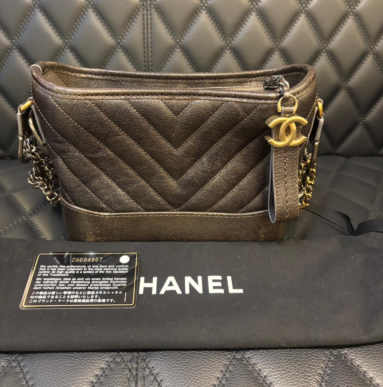 Petit Gabrielle en cuir caviar chevron vieilli. Gris foncé avec des détails en bronze. Légères éraflures et rayures sur le cuir, en particulier sur la partie inférieure. Légers plis sur le cuir. Série n°26. Livré avec son holo, sa carte et son sac à