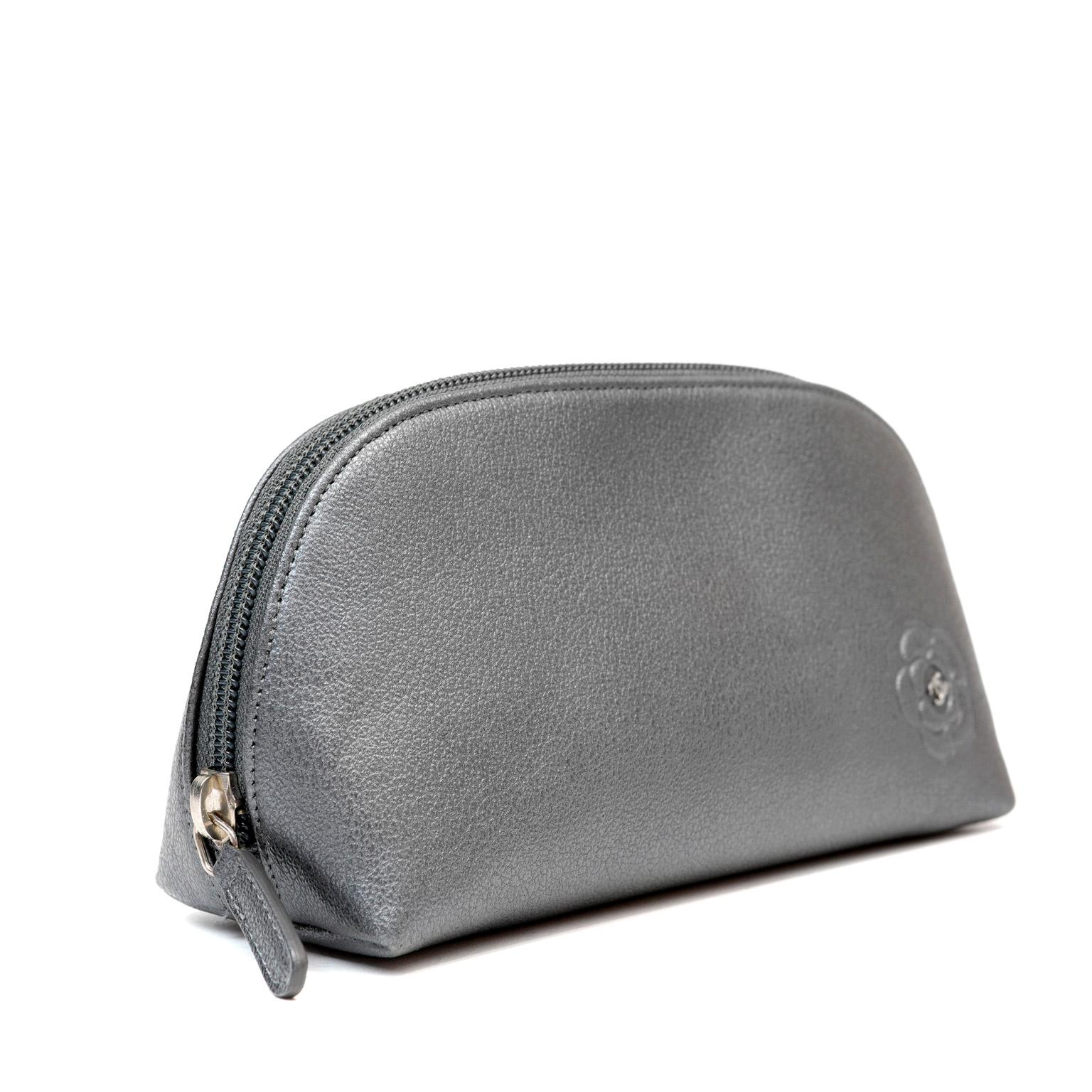 This authentic Chanel Small Slate Grey Camellia Pouch is in excellent plus condition.  Perfect for cosmetics or other small necessary items, this chic pouch is a great find.  Slate grey domed leather pouch with zippered top opening.  Clean fabric