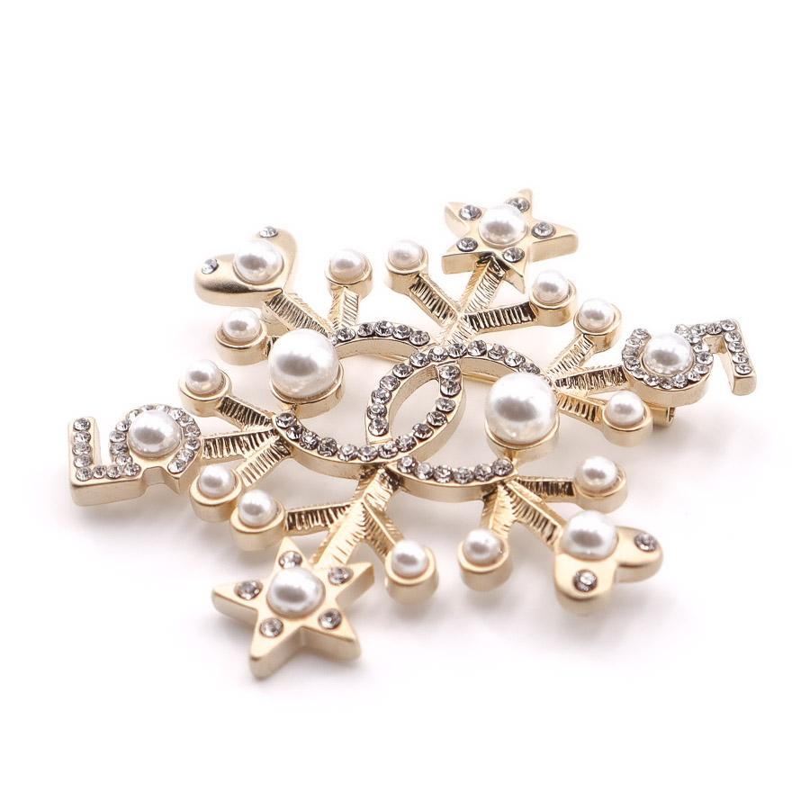 Superb jewel from Maison CHANEL. A star-shaped brooch on a metal base gilded with fine gold, on which pearl beads and rhinestones are set. Each end of the brooch ends with a small star and then a small heart motif. In the center of the spindle, a