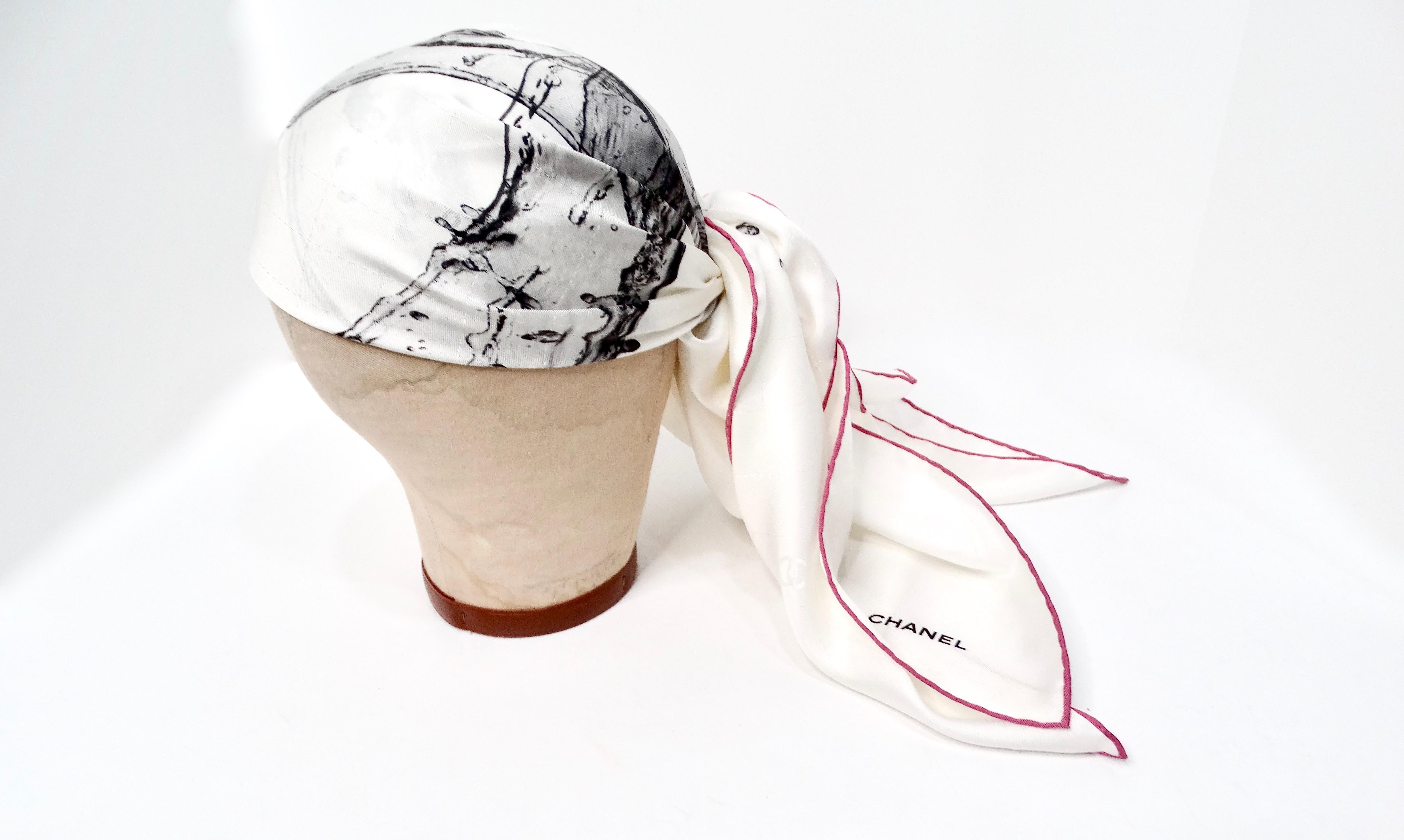 The Chanel Splash Interlocking CC Printed Ivory Silk Scarf is a timeless accessory that effortlessly embodies the brand's renowned luxury and sophistication. Crafted from pure silk, this elegant scarf features a striking ivory base adorned with bold