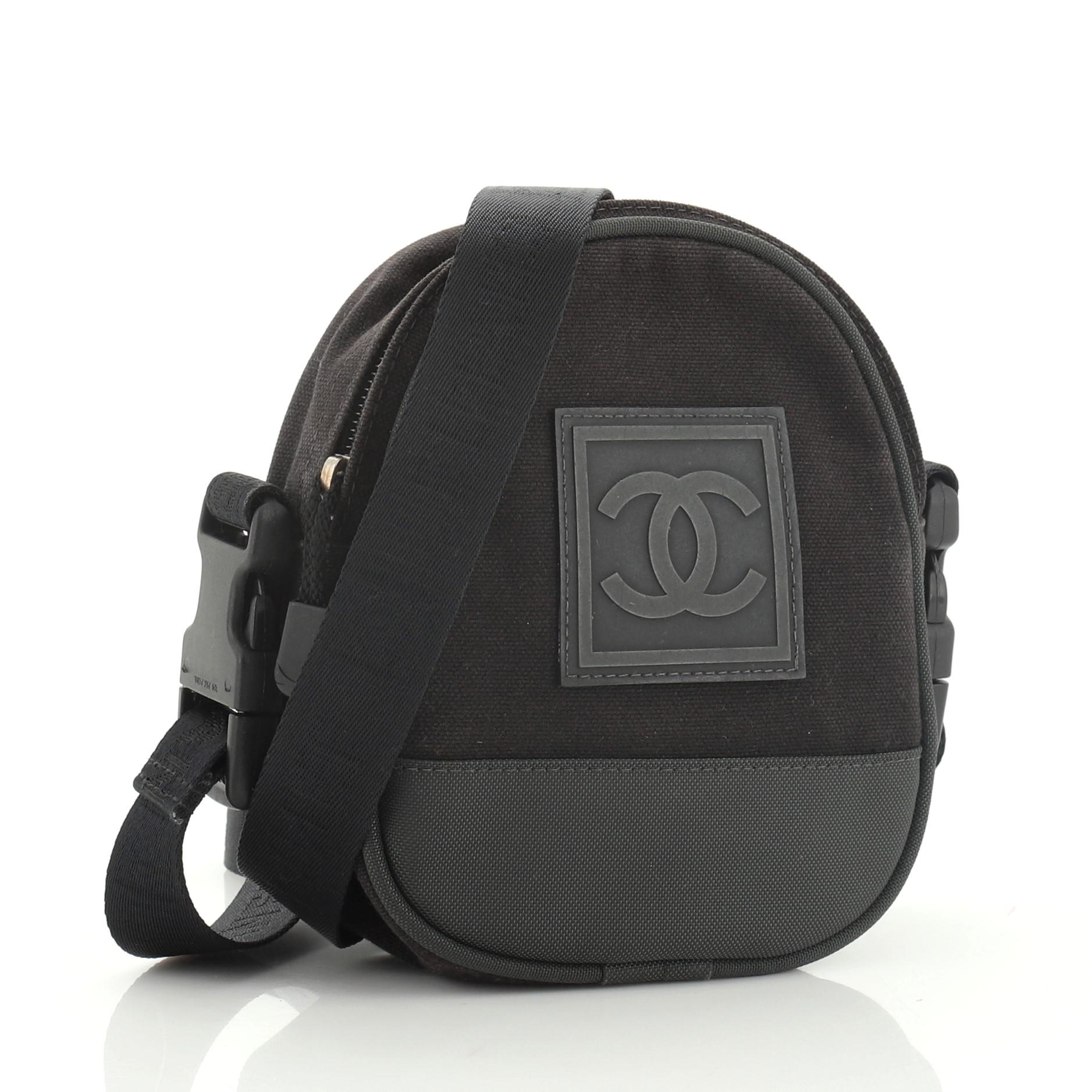 This Chanel Sport Line Crossbody Bag Nylon Mini, crafted from black and green nylon, features a removable canvas strap, CC logo on the front, and silver-tone hardware. Its zip closure opens to a green nylon interior with slip pocket. Hologram