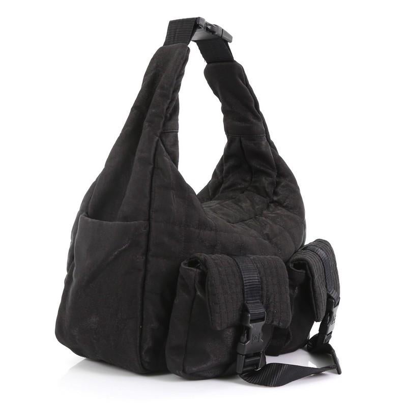 This Chanel Sport Line Double Pocket Shoulder Bag Quilted Nylon Medium, crafted in black quilted nylon, features adjustable strap, exterior front pockets with buckle closure and side slip pockets, and silver-tone hardware. Its zip closure opens to a