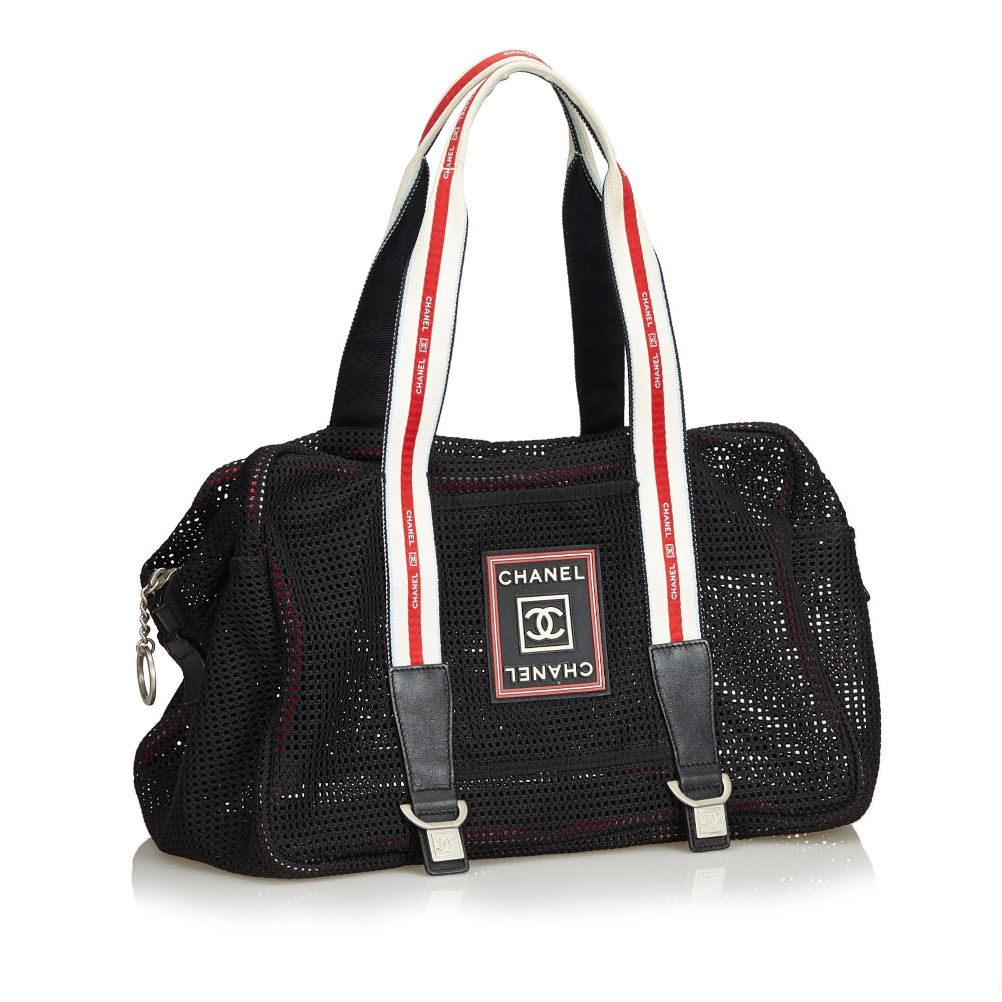 This sporty Chanel shoulder bag features a black chemical fiber body with leather trim, front exterior slip pocket, striped flat shoulder straps, top zip closure, and interior zip pocket, which Chanel logo plaque on front. Comes with dust bag.