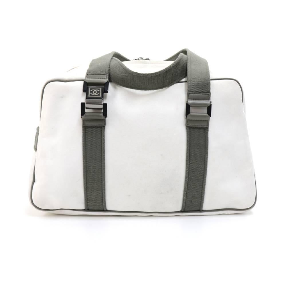 Chanel White Canvas Boston Bag from the Chanel Sports Line. Outside has one slip pocket in the front and gray trim and fabric straps with Chanel buckles. Inside has a spacious interior White nylon lining and one zipper pocket. Great for your sports,