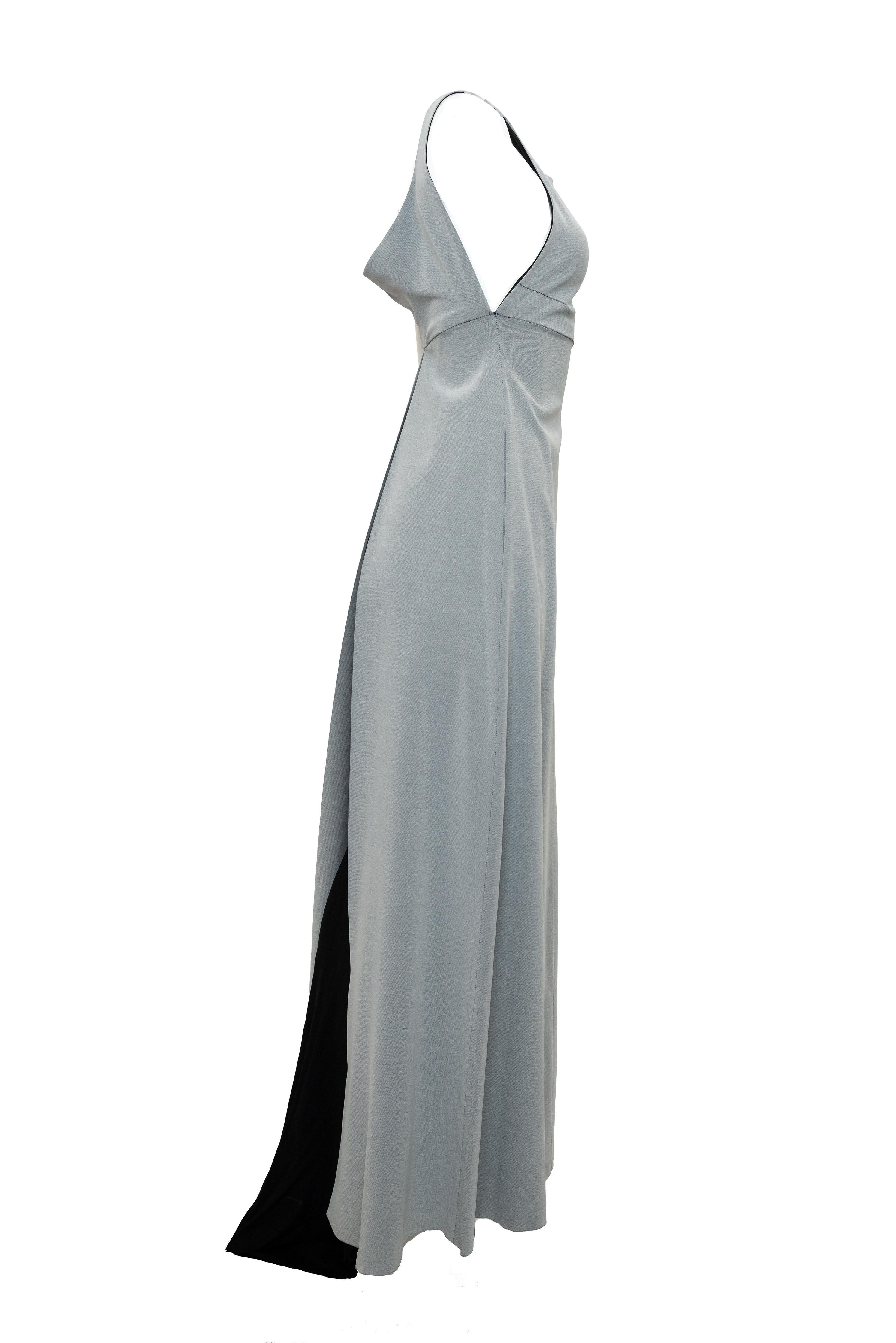 This exquisite Chanel gown from the Spring 1998 runway embodies timeless elegance with its sophisticated silhouette. The flowing gray fabric is anchored by a dramatic black train that commands attention, while the empire waist creates a graceful,