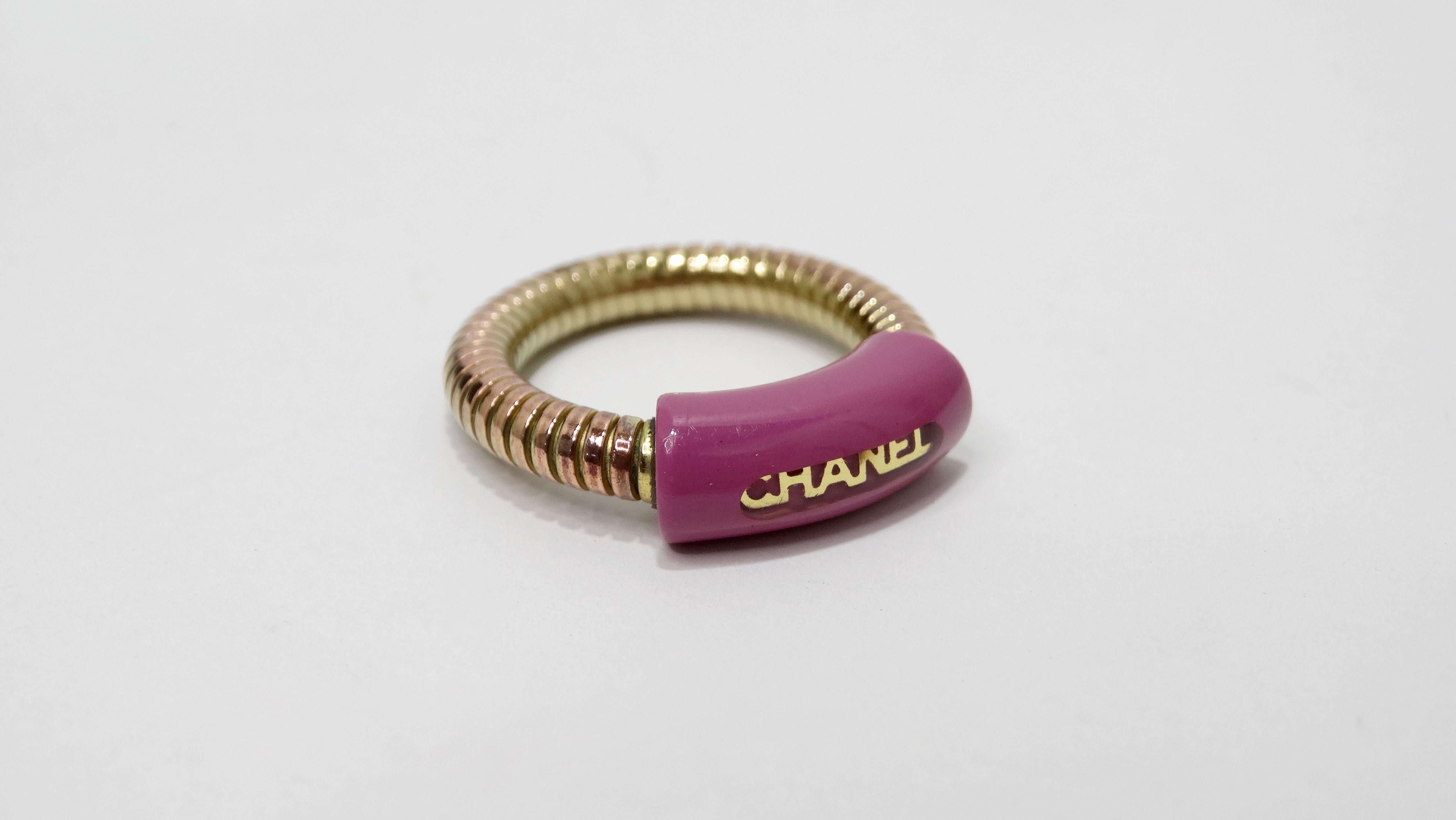 The perfect ring for every Chanel lover! Circa 2001 from their Spring collection, this ring features a gold-toned ribbed band wrapped with magenta colored resin and stamped 