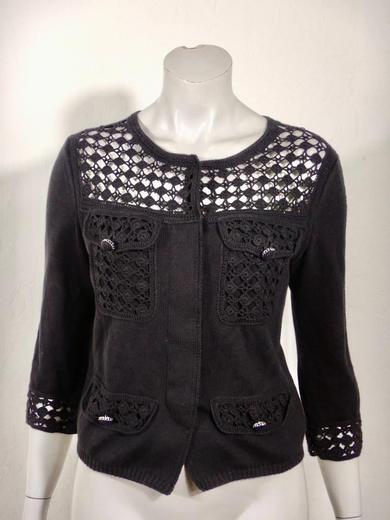 Chanel black cotton knit cardigan sweater with knit lace detail. Hidden button closure. There are two snaps to close the sweater at the neckline. I'm not certain but I believe one snap may have been added (not original to the sweater) to ensure that