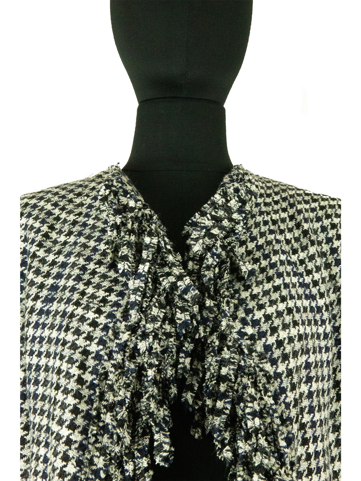 From the Chanel collection of spring 2007, comes this unique black and white dogtooth jacket. The bodice is loose fitting and cut on the bias, to give the two fronts of the jacket a draped feeling, as they fall into one another. There is also frayed