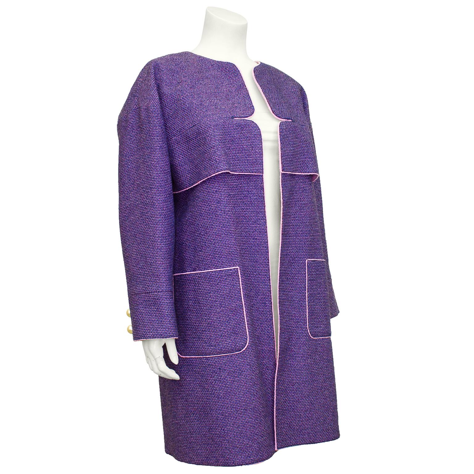 Stunning purple and pink tweed coat from the Chanel Spring 2013 collection. Collarless and open front with a vent detail at bust and two large patch pockets at hips. Dropped shoulder and large faux pearl buttons at cuffs. Interior is the perfect