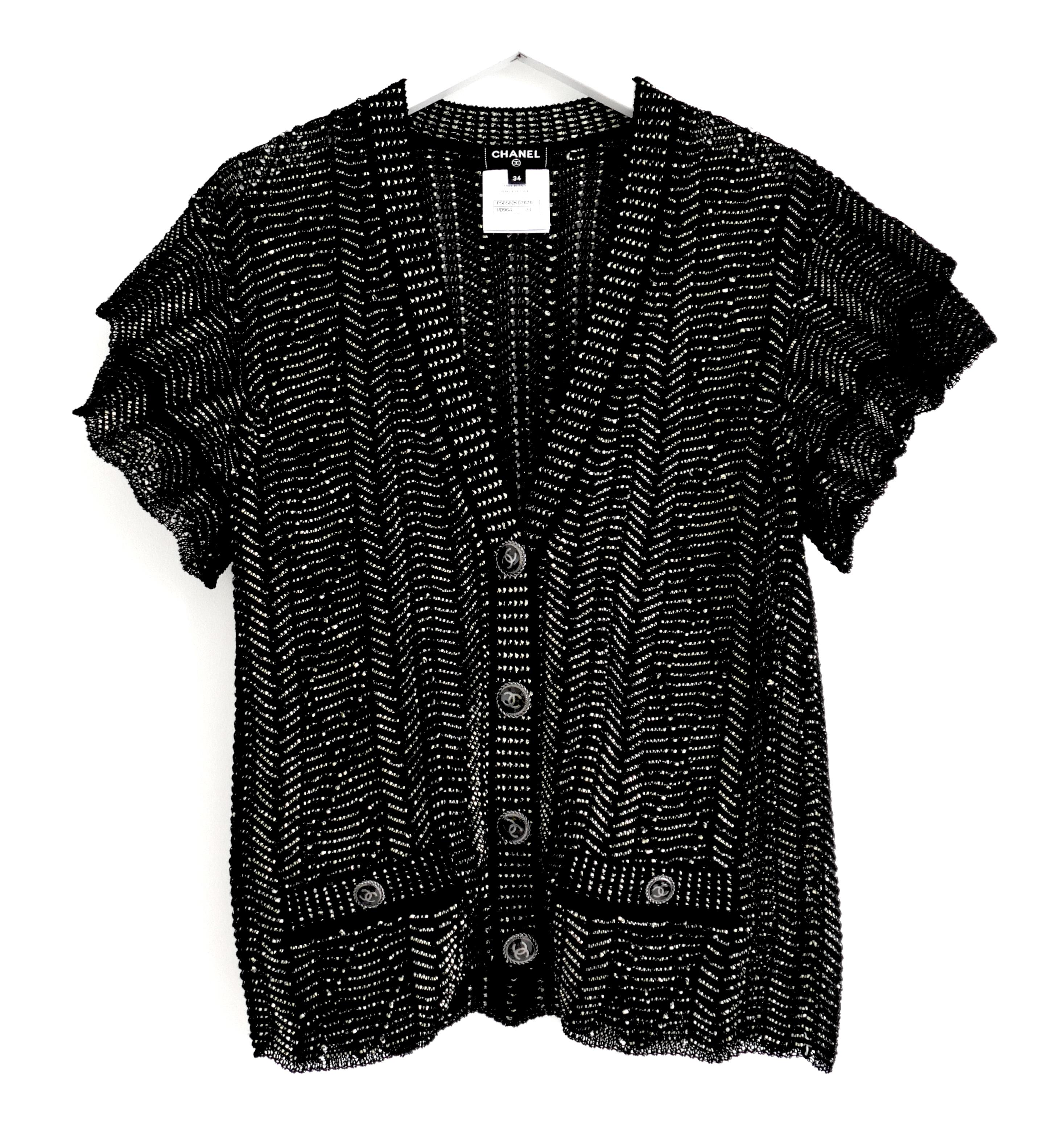 Magnifique cardigan Chanel issu de la collection printemps 2018. Non portés. u2028Réalisé en coton, polyamide et papier noir et or, avec des boutons en argent émaillé CC noir.  Il présente un ourlet délicatement festonné, de petites poches sur le