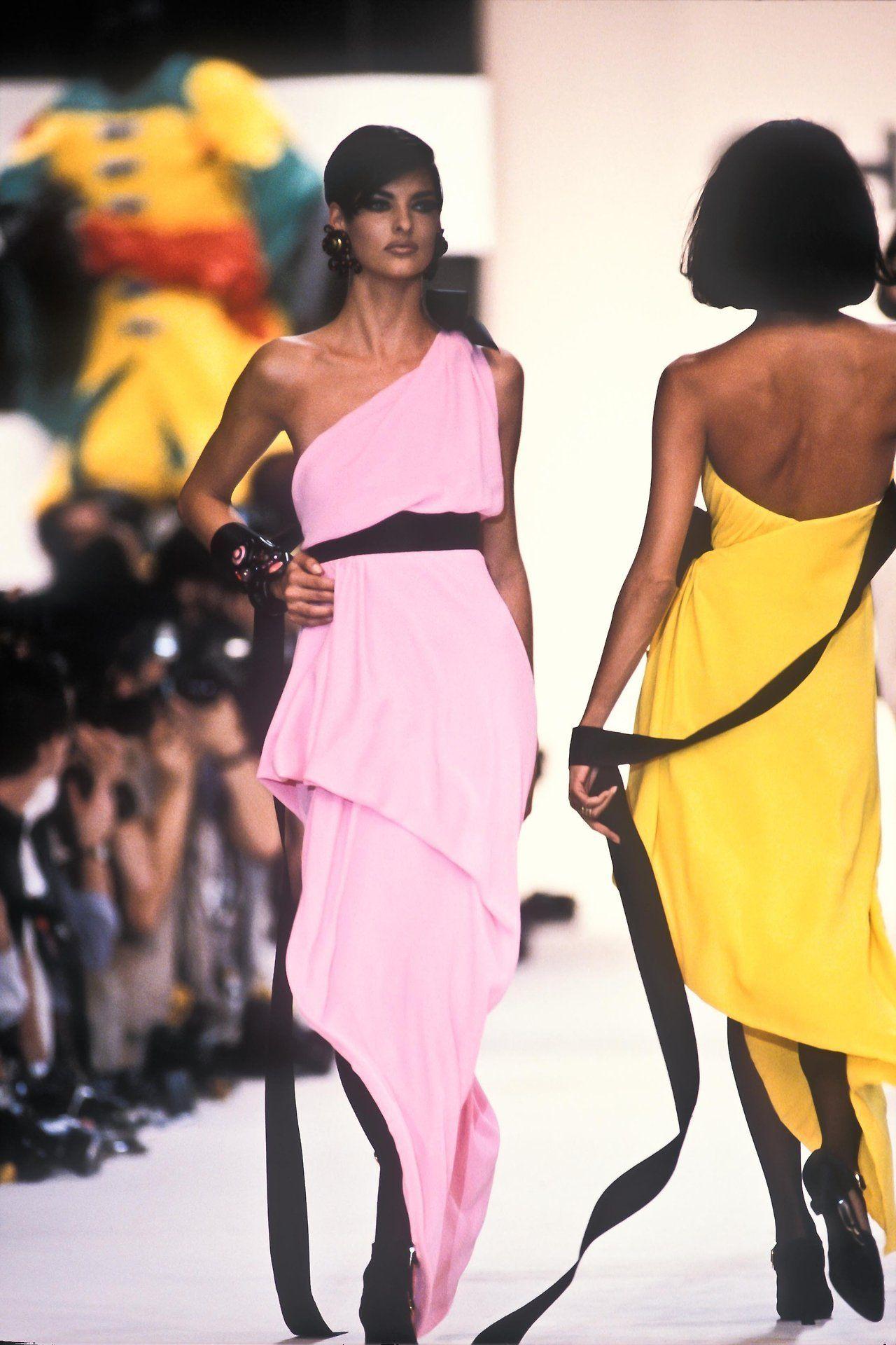 Vintage Spring Summer 1991 CHANEL cocktail dress features a gathered bustier strapless top, button slit skirt with asymmetrical hem, and extended ribbon train waistline applique that hangs off the back. Featured on Linda Evangelista in the ad