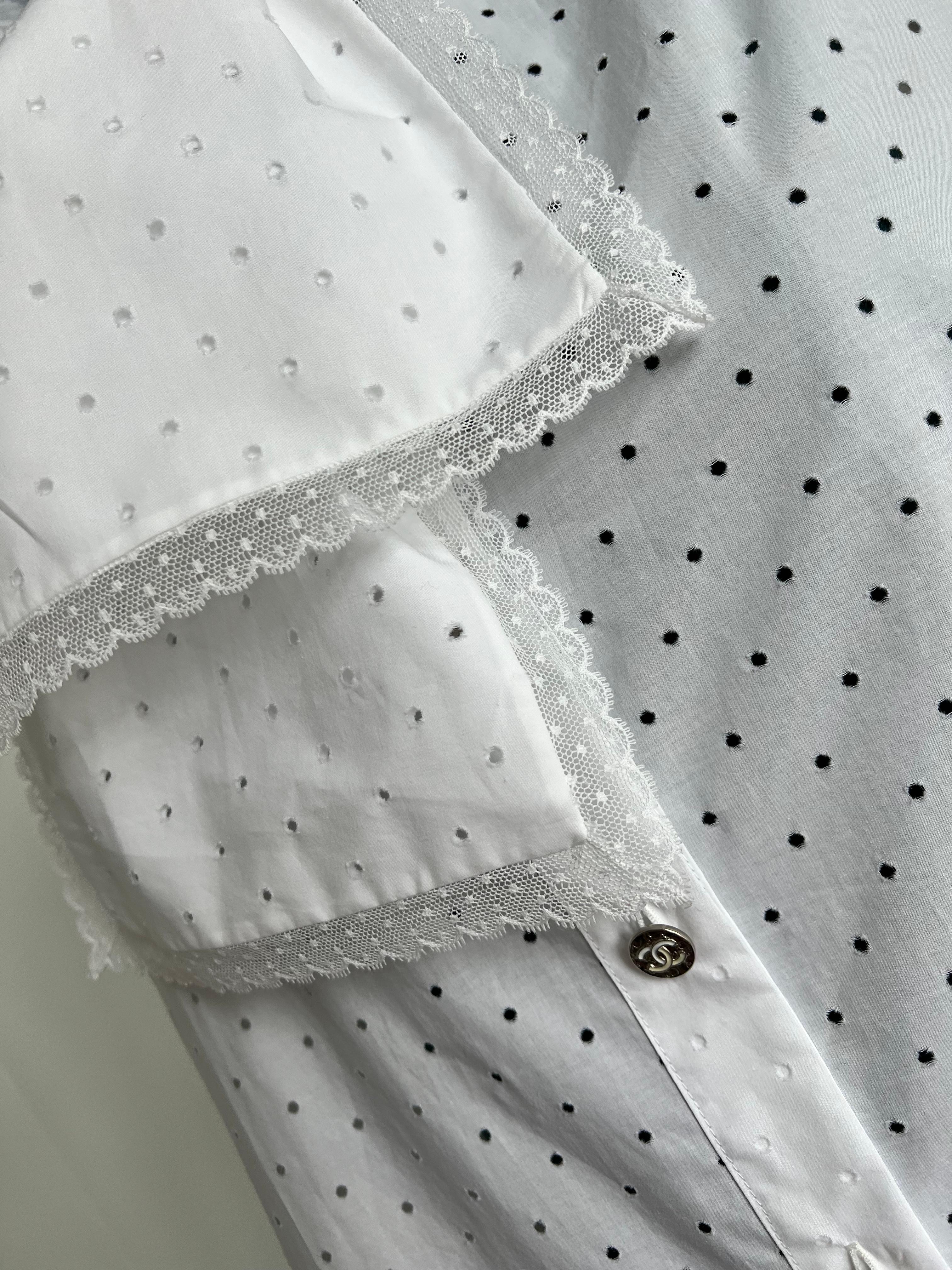 The Chanel SS23 white shirt with tuxedo bow tie detail and eyelid cut, lace trim is a stunning piece that perfectly embodies the brand's signature style. The shirt is made from high-quality cotton and features a classic white color that is versatile
