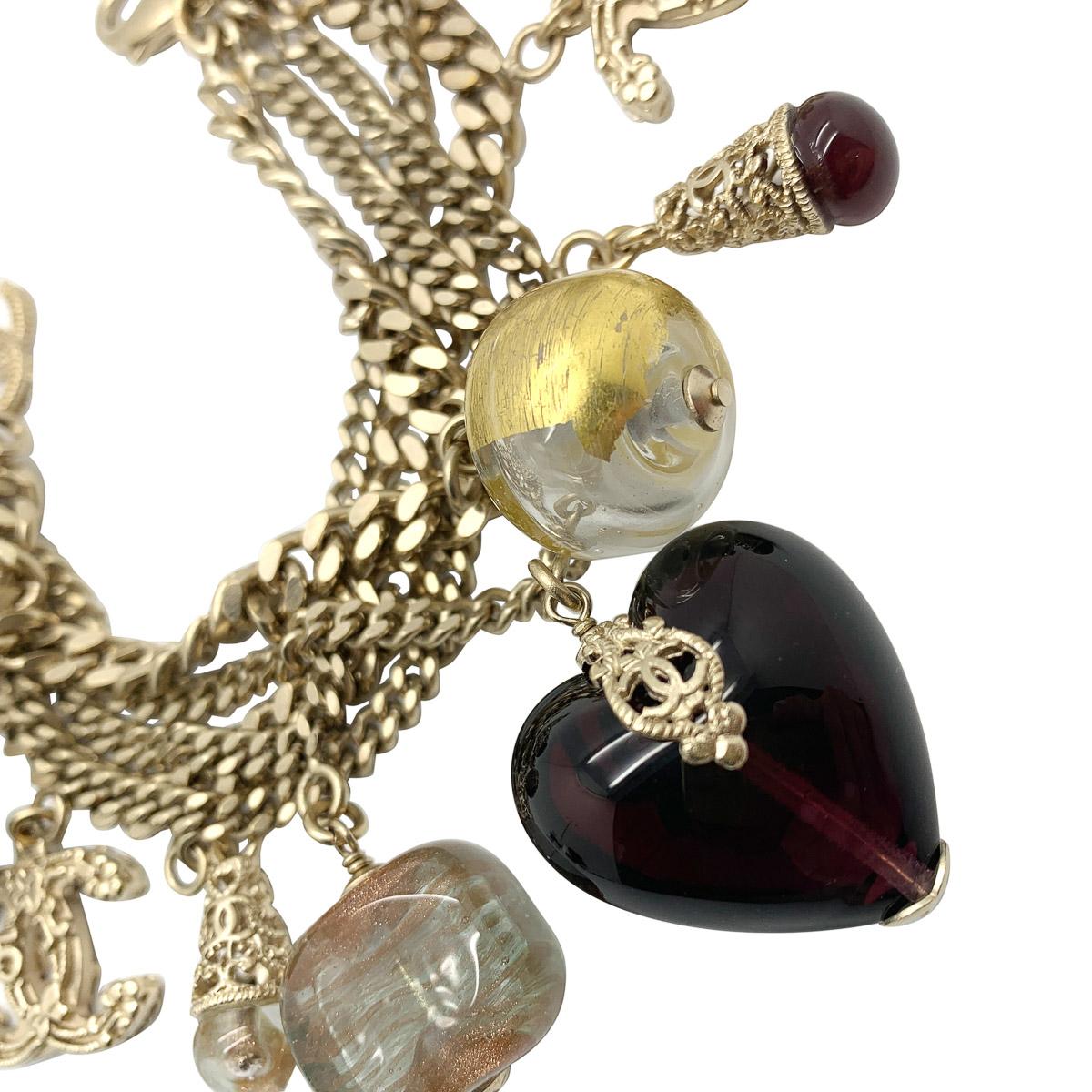 An exceptional Chanel Gripoix glass charm bracelet. Featuring an almost impossible display of charms. Amongst them logos, hearts, gripoix glass drops, balls set in filigree cages. The array of rich jewel colours against the antiqued gold metalwork