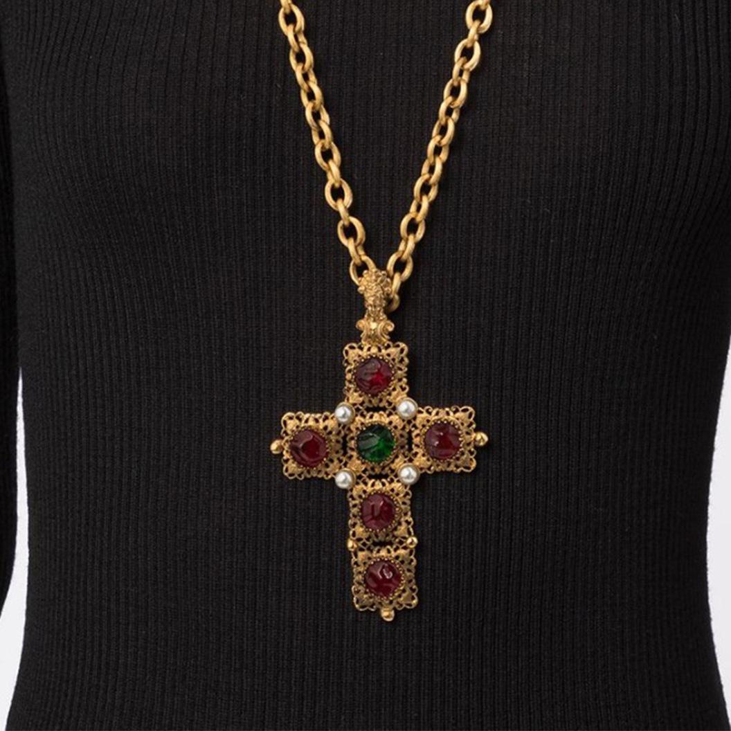 A breathtaking piece from Chanel, this vintage pre-owned necklace from the 1980s features a cross-style pendant with dark red and green Gripoix glass hanging from a chunky gold chain. Finished with a cutout design, the cross pendant features a