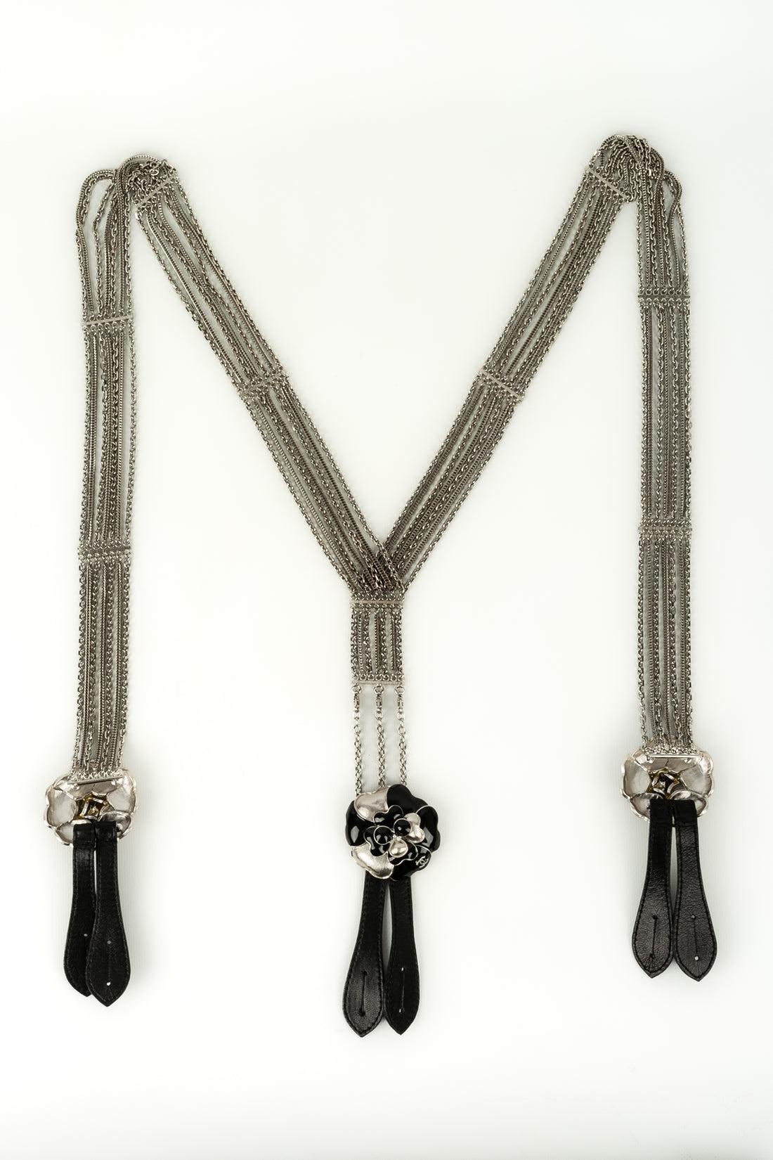 Chanel - Straps in silver chain, black leather and camellia in silver metal and black enamel. Spring-Summer 2007 collection.

Additional information:
Condition: Very good condition
Dimensions: Length front: 75 cm - Length back: 21 cm
Period: 21st