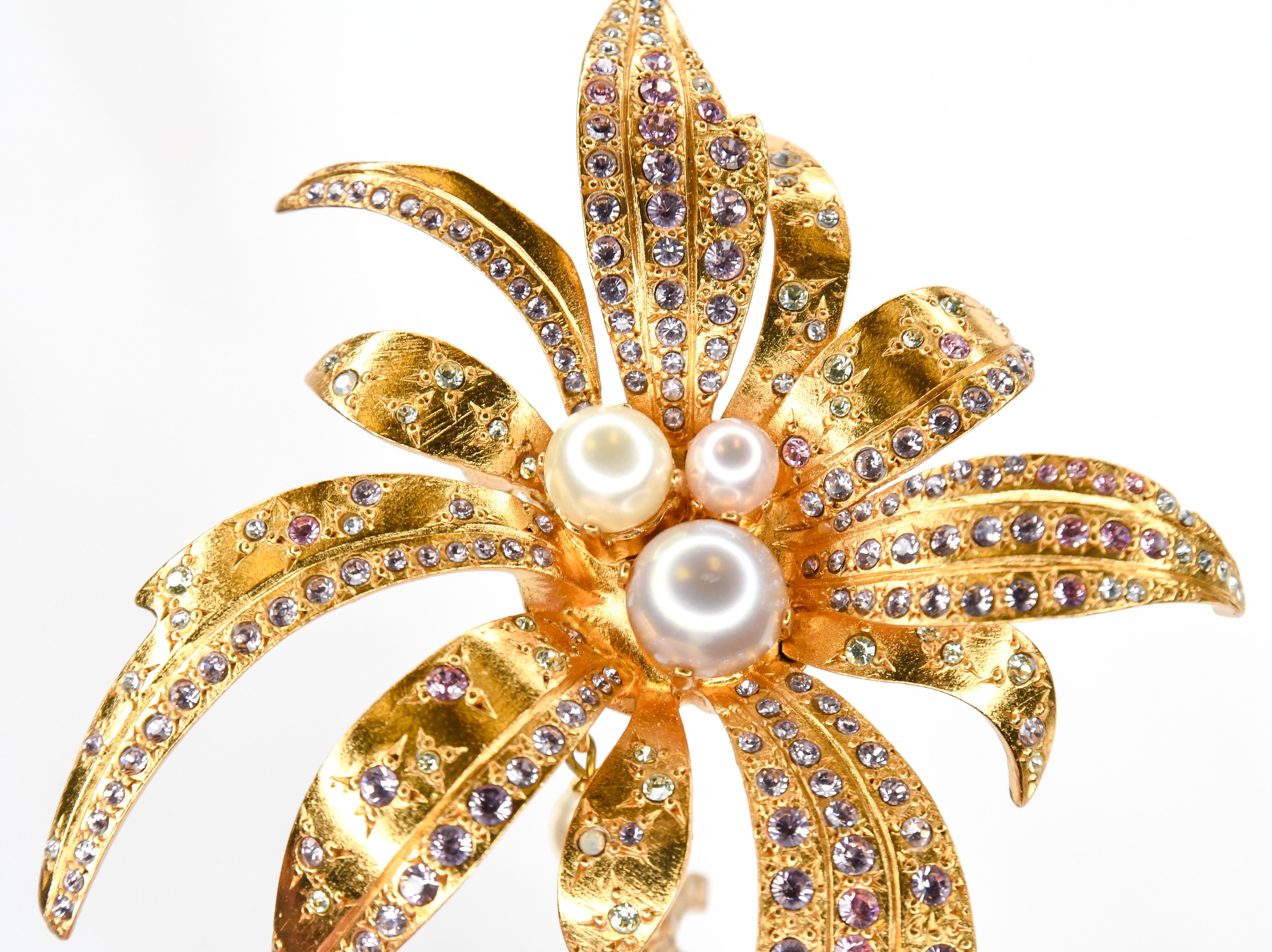 Chanel.  Sometimes that's all you need to know!  This amazing Chanel brooch in matte finish gold tone replicates a stylized flower with pearls at the center and leaves sprinkled with clear and pink gripoix stones.  A pearl topped CC logo with Aurora