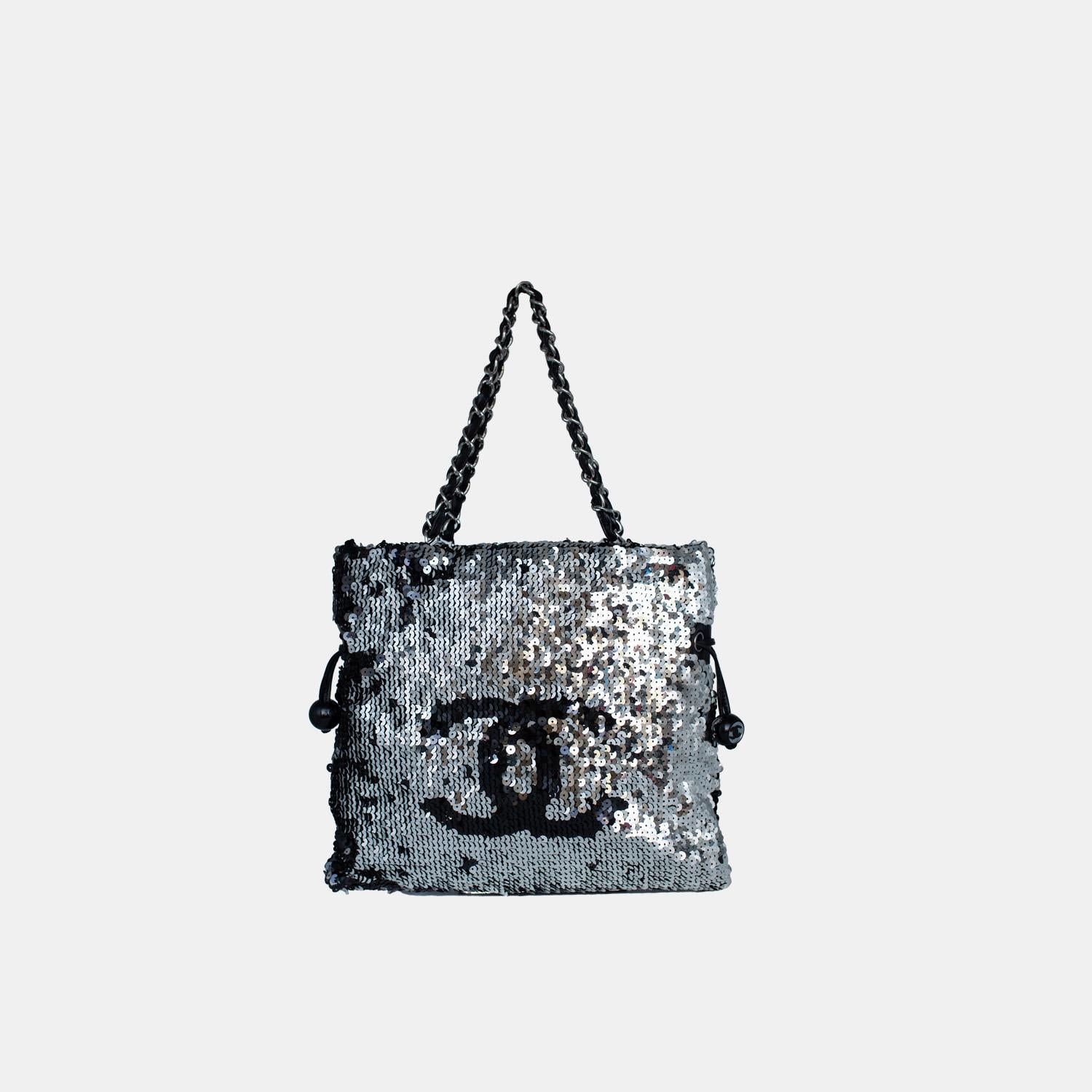 Introducing the Chanel Summer Nights Sequin Drawstring Tote Small SHW, a timeless and fashionable bag for any occasion. This exquisite bag features mesmerising sequins, chain-leather handles, and the iconic CC logo. The drawstring closure reveals a