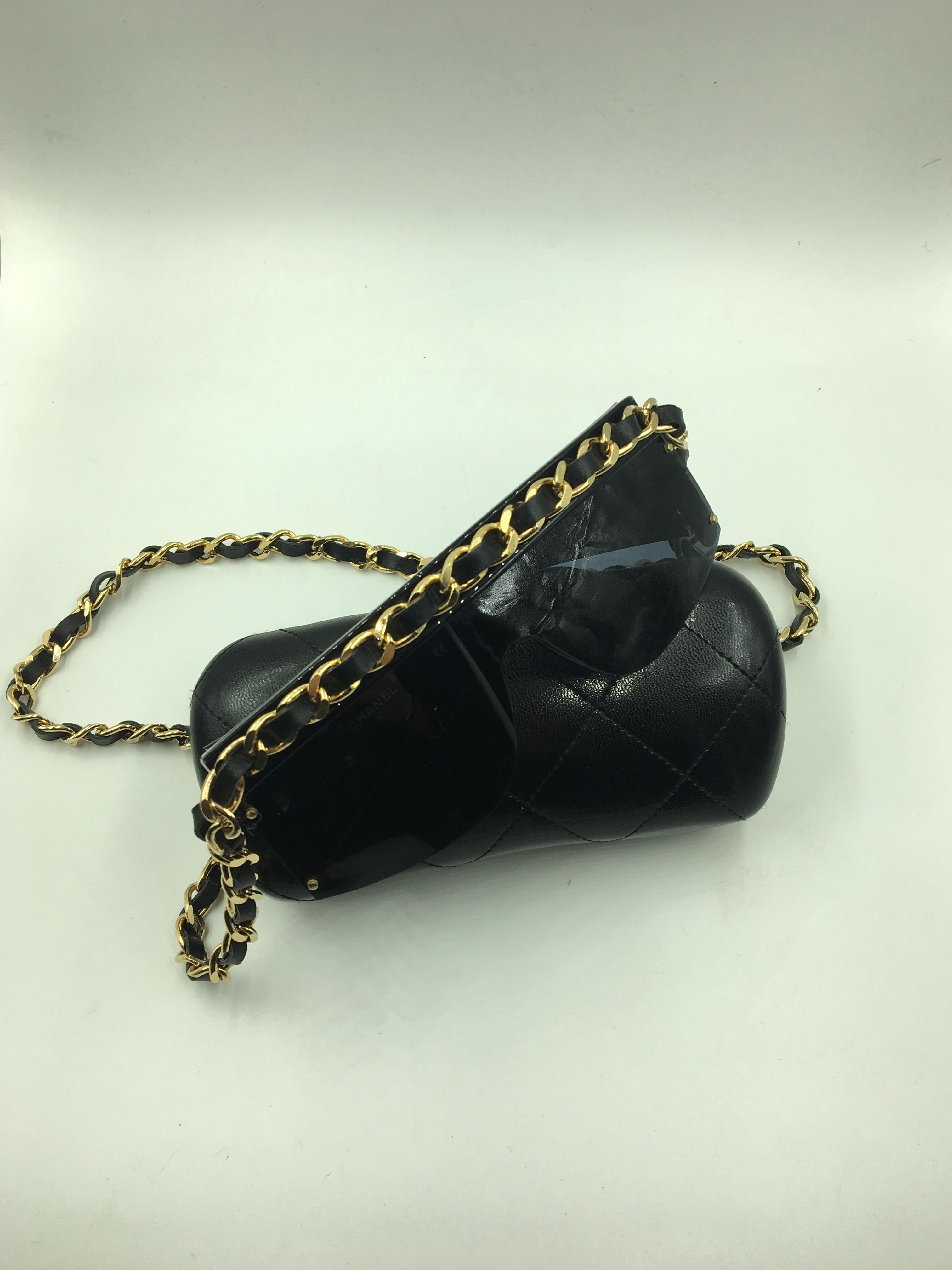 Authentic sunglasses from Chanel with black frames and gold neck strap. The neck strap runs across the top of the frames and is a classic leather laced strap. 
Each arm of the sunglasses in adorned with a large gold tone CC.

In Very Good Conditio,