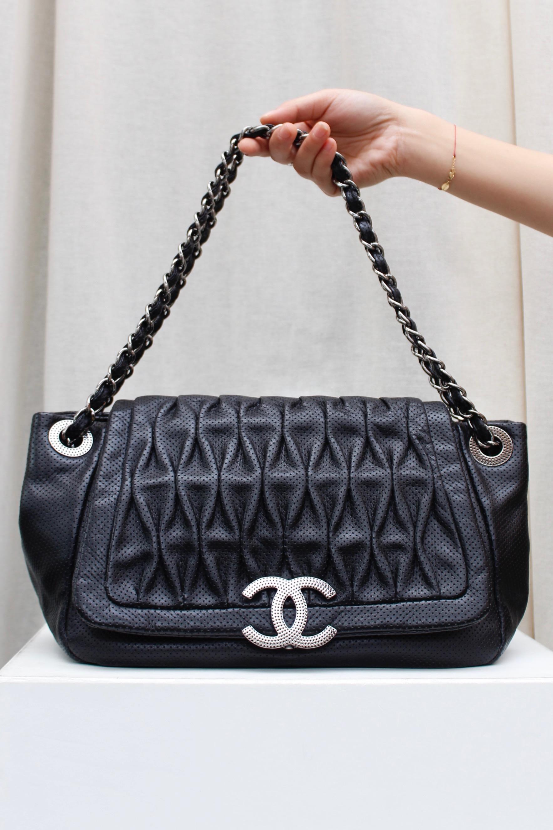 CHANEL (Made in Italy) Superb bag composed of perforated pleated black veal skin. It can be carried over the shoulder or cross-body by means of two sliding handles composed of silver plated chain entwined with black leather. The bag offers a