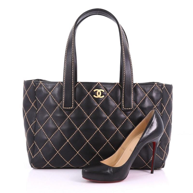 This Chanel Surpique Tote Quilted Leather Large, crafted from black quilted leather, features dual flat leather handles, contrast stitching, and gold-tone hardware. Its magnetic snap closure opens to a black fabric interior with zip pockets.