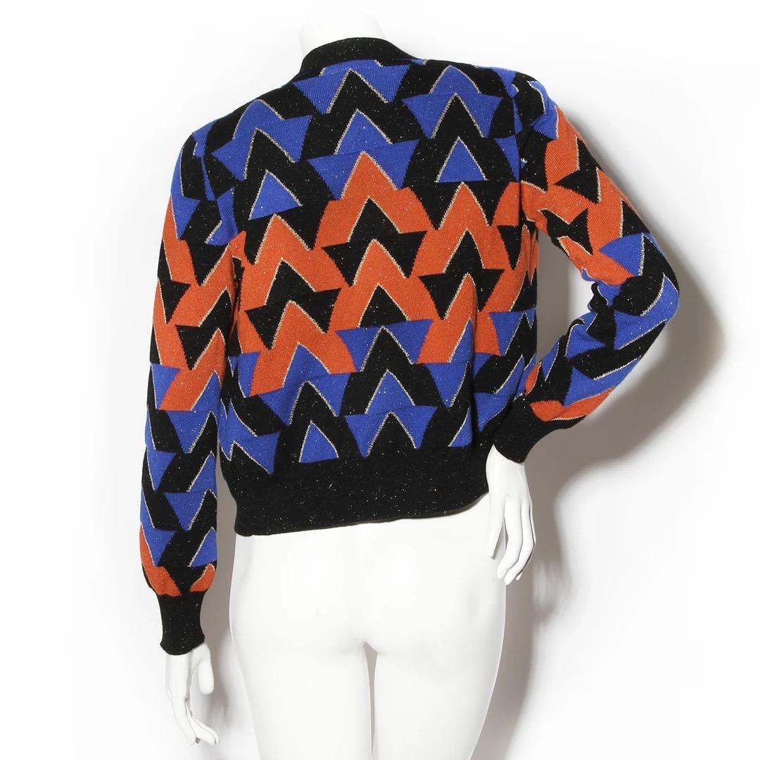 Chanel by Karl Lagerfeld for Chanel - Set di maglioni con cardigan 
Pre-Autunno 2019 
Prodotto in Italia 
Arancione, nero e blu 
Maglia in lurex oro 
Motivo geometrico 
Bottoni a forma di scarabeo blu e oro sul davanti del cardigan 
Dettagli in