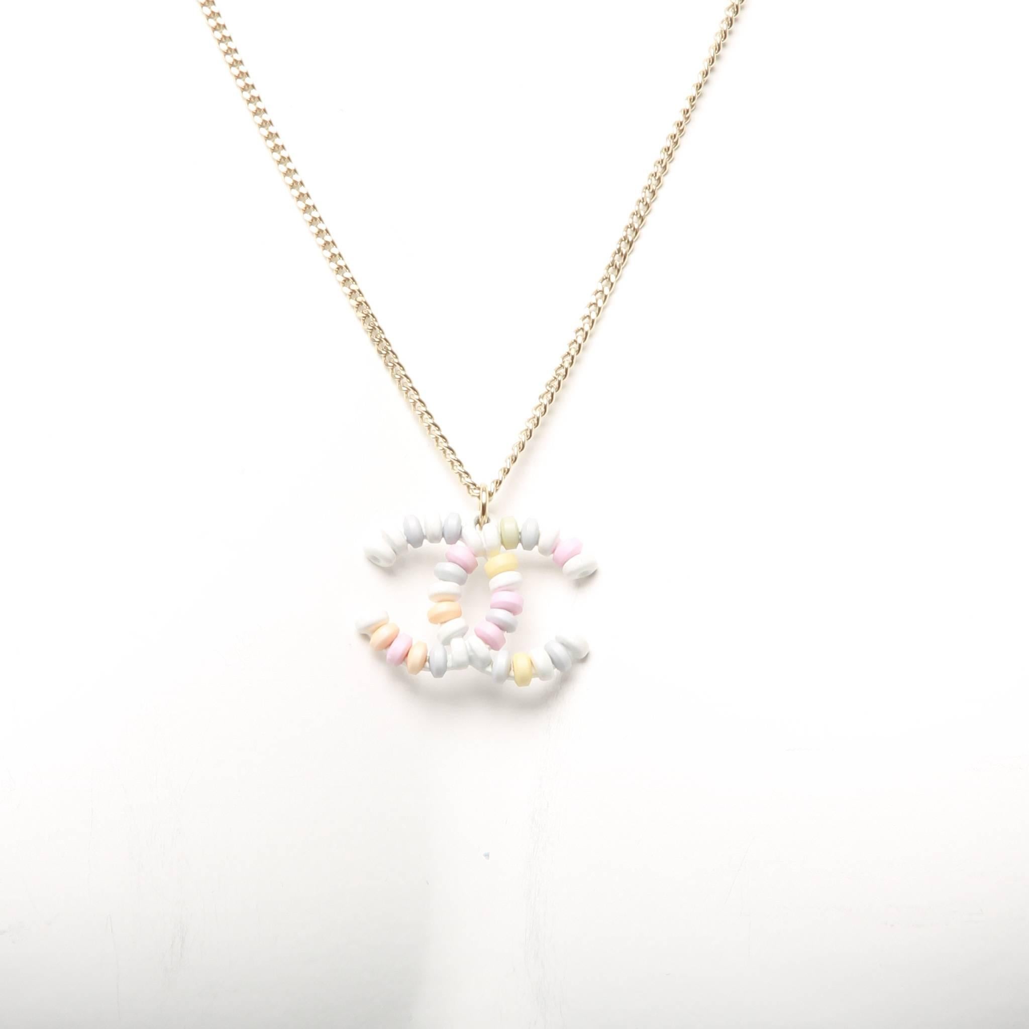 Limited edition. From the Pre-Spring 2014 Collection. White and multicolor Chanel resin beaded interlocking CC pendant on a simple very pale gold-tone chain with lobster clasp closure. Includes authentic pouch and box. 

Chain features two links