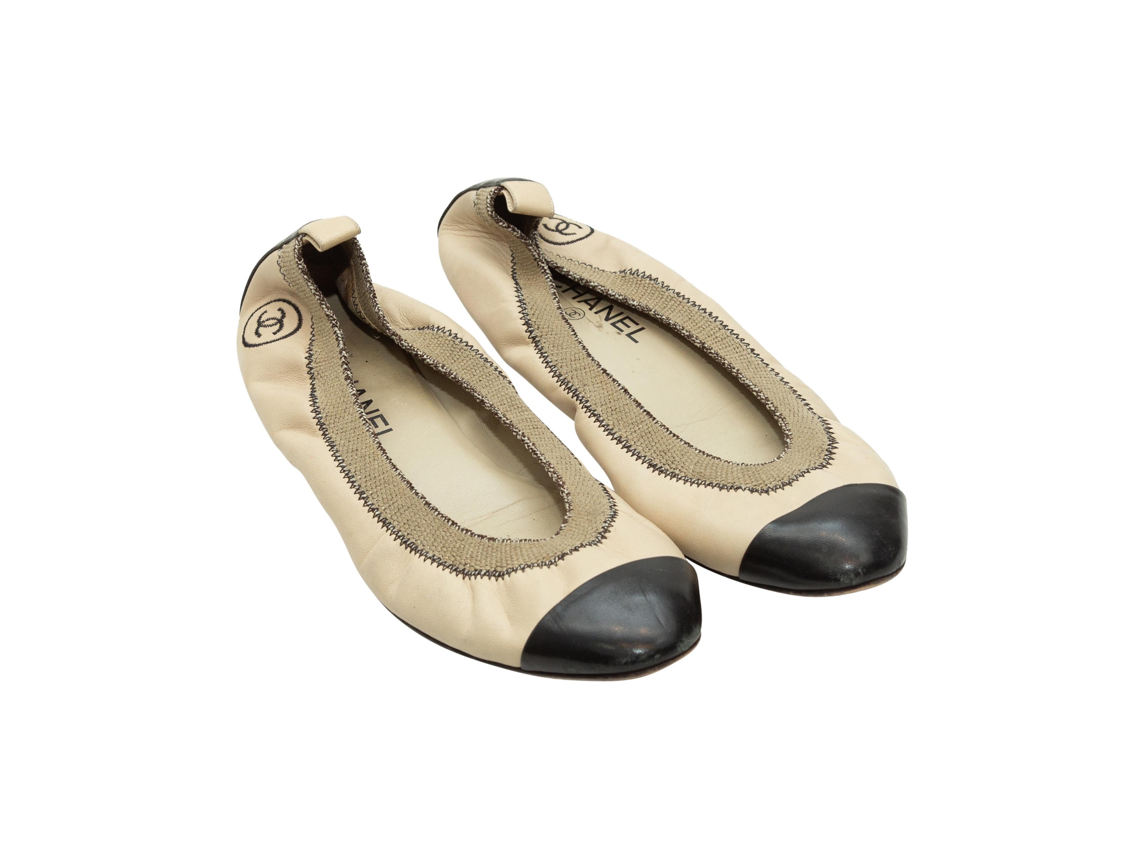 Product details: Tan and black cap-toe ballet flats by Chanel. CC embroidery at heels. Designer size 41. 
Condition: Pre-owned. Good. Wear throughout.