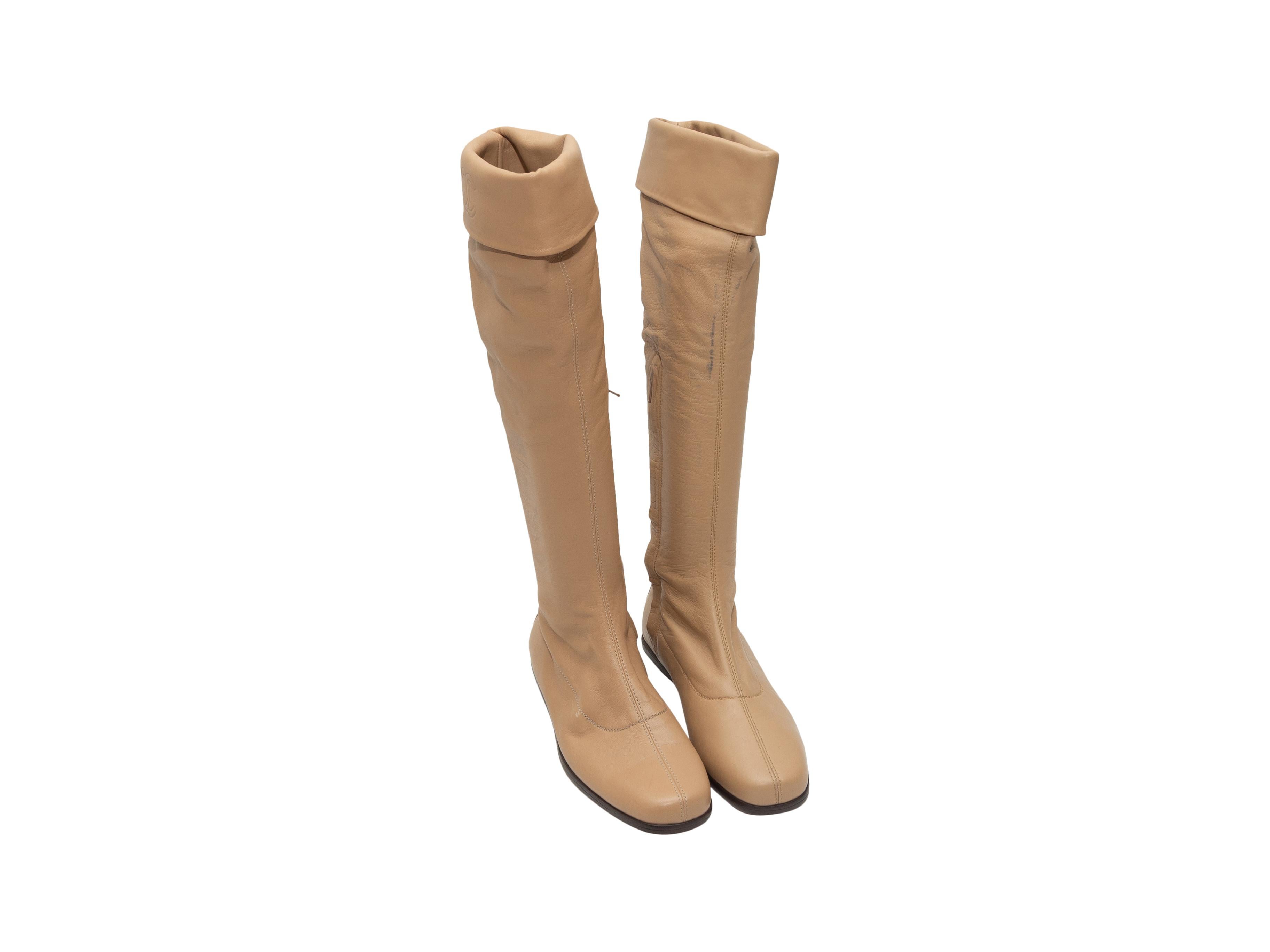 Product details: Tan leather knee-high boots by Chanel. Embossed CCs at outer tops. Zip closures at inner sides. Designer size 36. 0.5