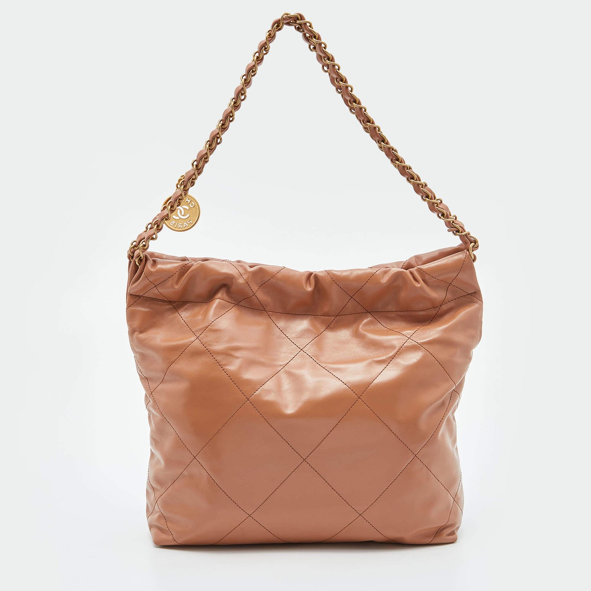 The Chanel 22 bag is a luxurious and chic accessory. Crafted from premium leather with a glossy finish, this drawstring bag features the iconic quilted design synonymous with Chanel. Its compact size and convenient drawstring closure make it a