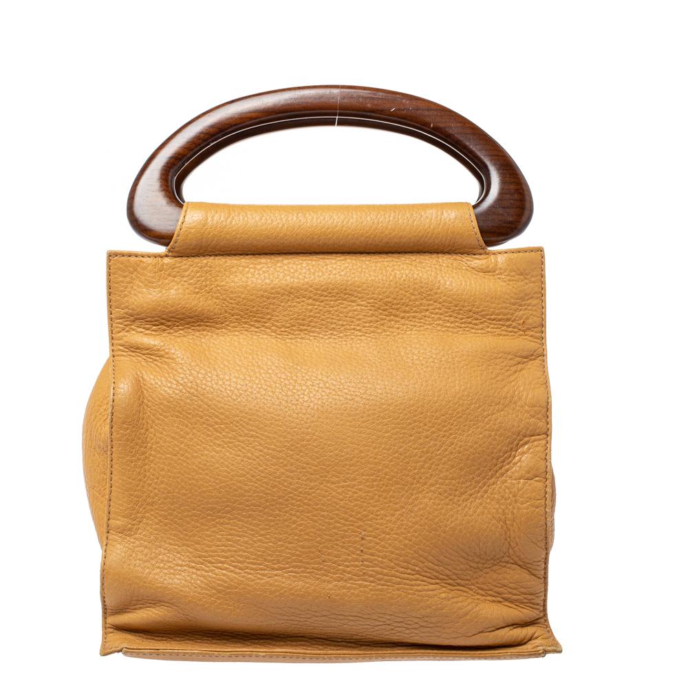 Die aus weichem:: genarbtem Leder gefertigte Tasche ist mit ihrer einzigartigen Silhouette und den Holzgriffen ein echter Hingucker. Der Innenraum ist mit Nylon gefüttert und wird mit einem Druckknopfverschluss gesichert. Diese Handtasche aus dem