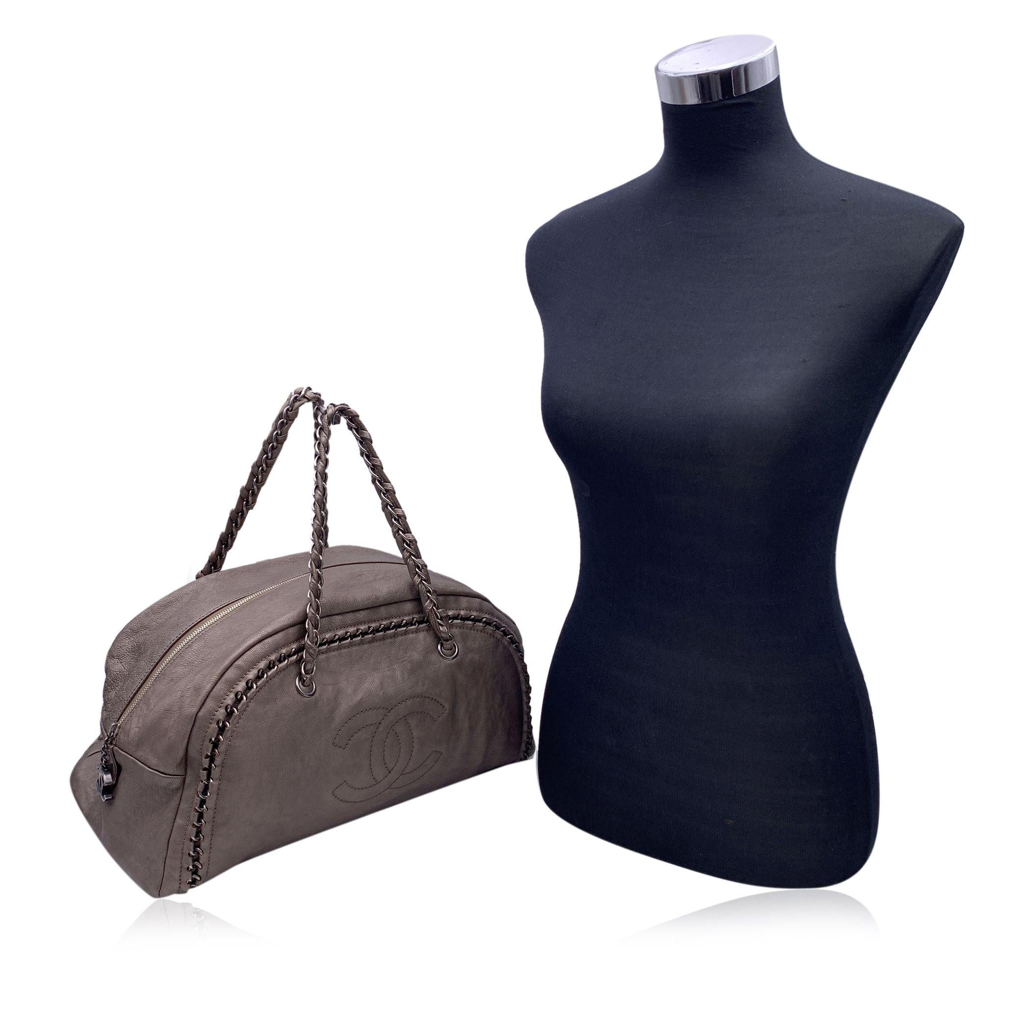 Beautiful taupe metallic leather 'Chain Around - Luxe Ligne' bowling bag by CHANEL with CC Chanel logo on the front and chain around detailing at the front and back. Silver metal hardware. Upper zip closure and CC logo zipper pull. Double braided