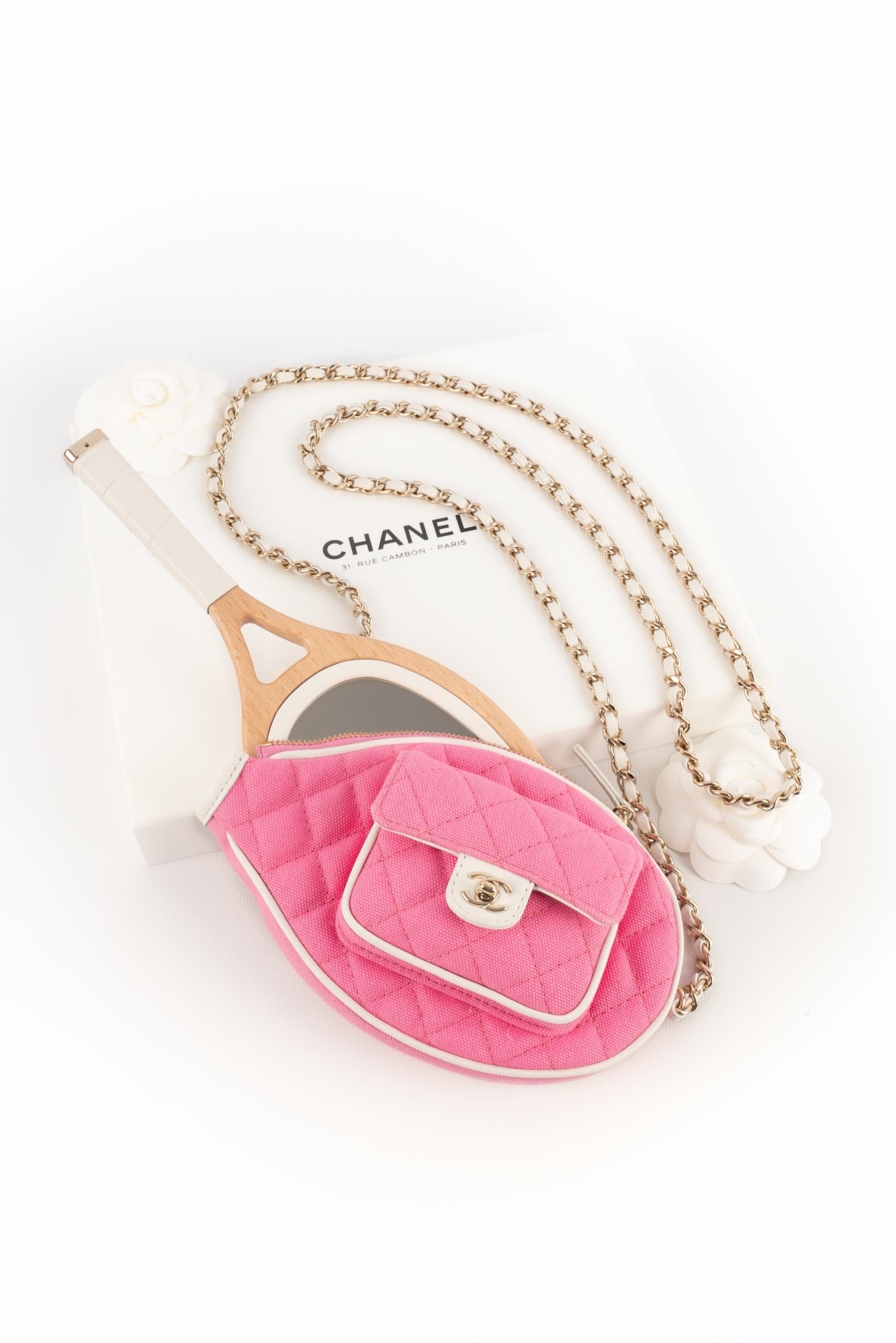CHANEL - (Made in France) Leather and wood hand mirror shaped as a tennis racket, with its pink cotton and white leather slipcover. Golden metal chain strap interlaced with white leather. Piece with a serial number. 2023 Cruise Collection, under the