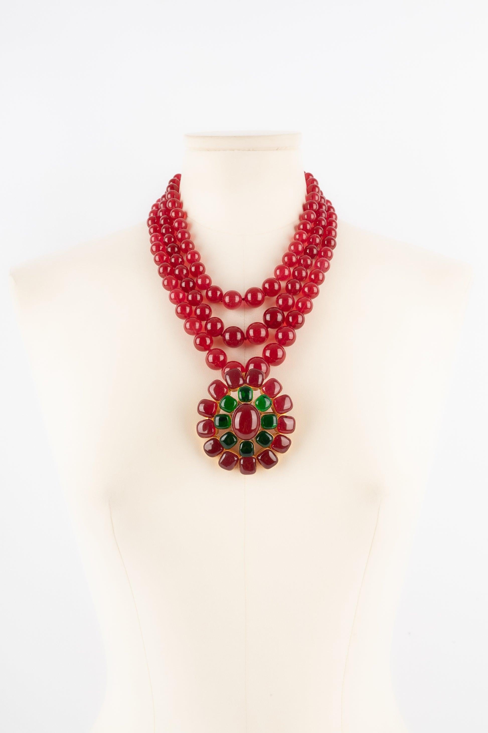 Chanel - (Made in France) Three-row red glass paste pearl necklace holding a golden metal pendant brooch with glass paste.

Additional information:
Condition: Good condition
Dimensions: Length: from 45 cm to 48 cm

Seller Reference: CB4
