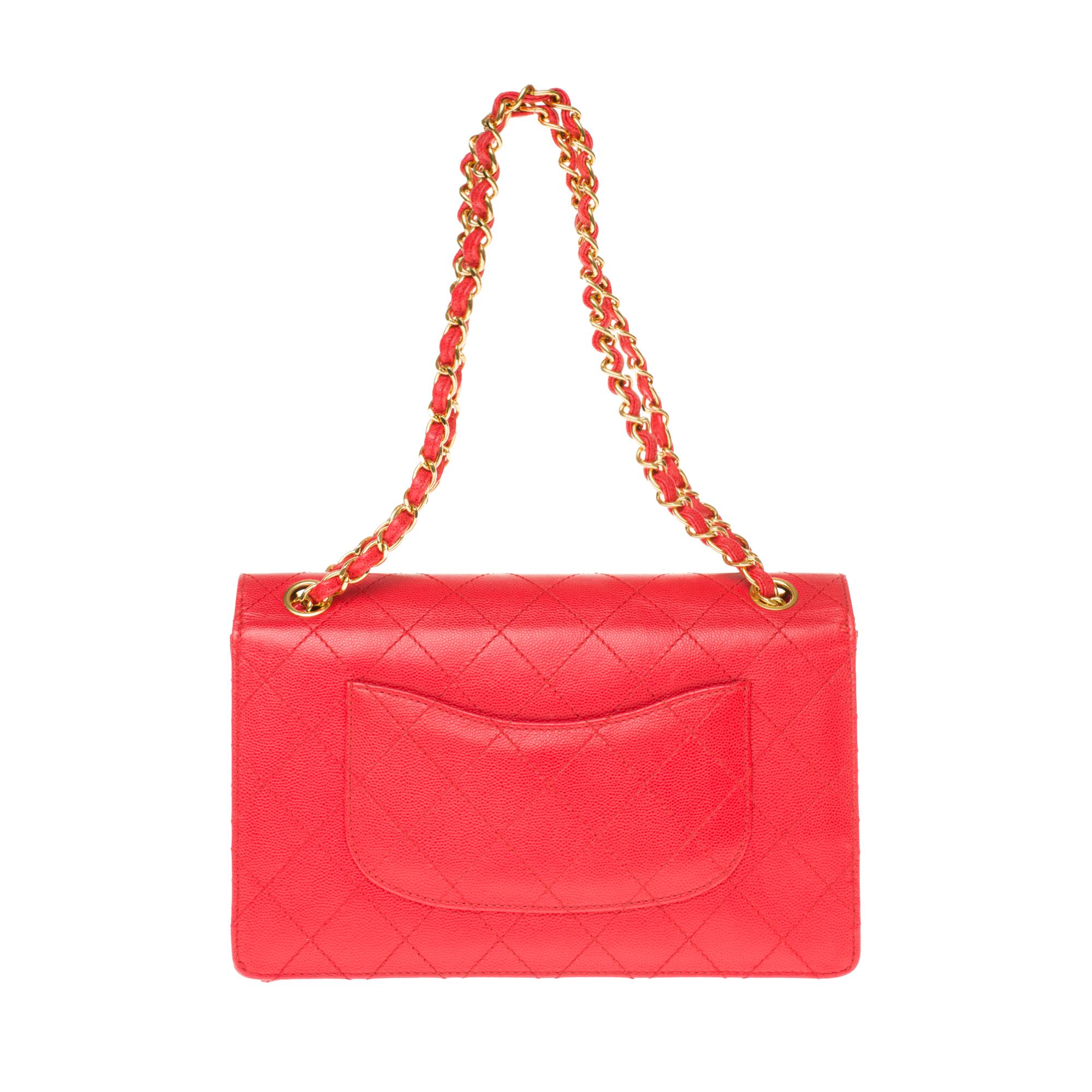 The iconic Chanel Timeless Handbag in red padded grained leather, gilded metal trim, a golden metal chain handle intertwined with red leather allowing a hand or shoulder support.

Gold-tone metal flap closure.
A patch pocket on the back of the