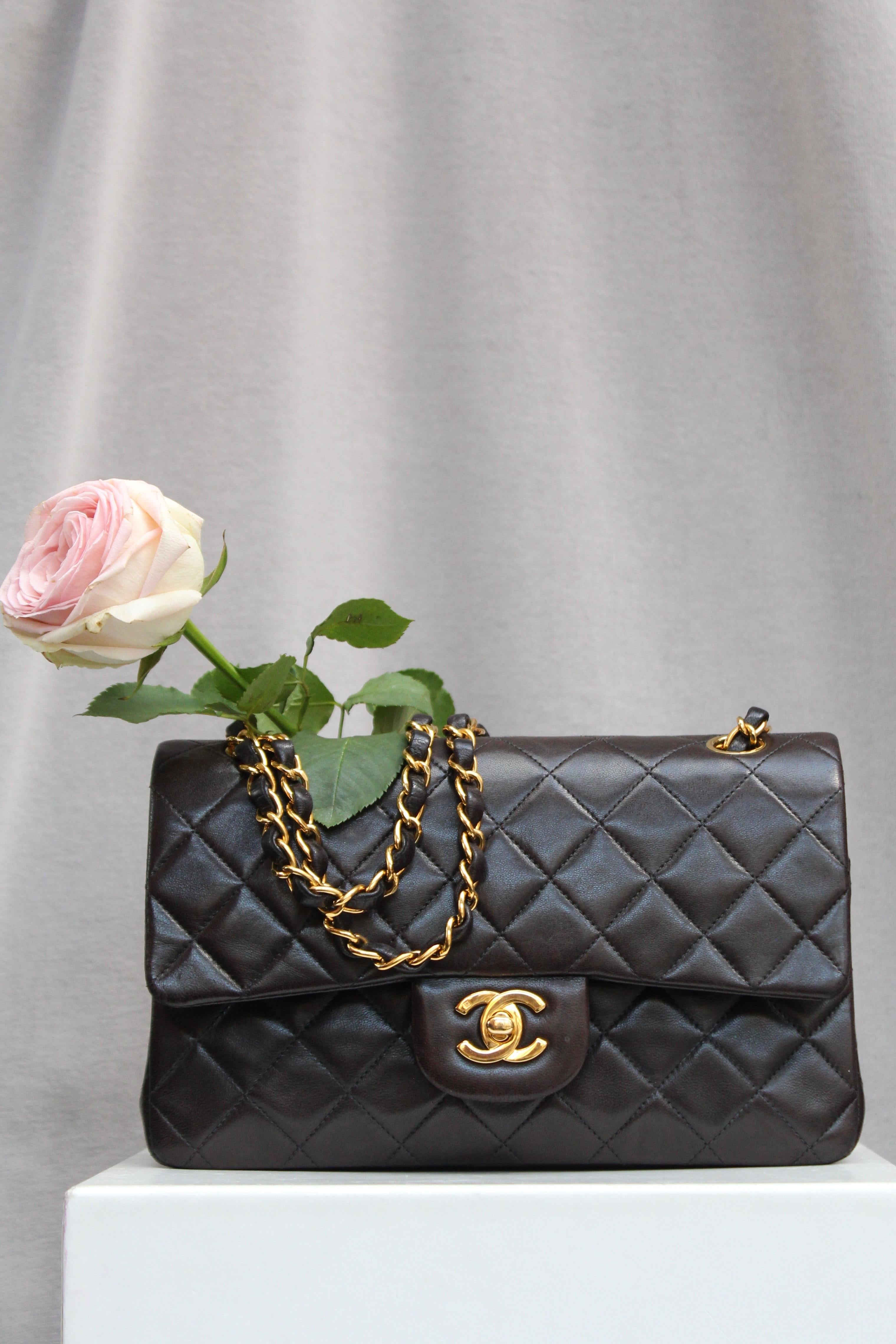 CHANEL – Iconic classic “Timeless” bag in brown quilted lambskin, with its double flap and gilded metal hardware.It can be worn over the shoulder or cross-body thanks to a double sliding chain entwined with brown leather. The back features a patch