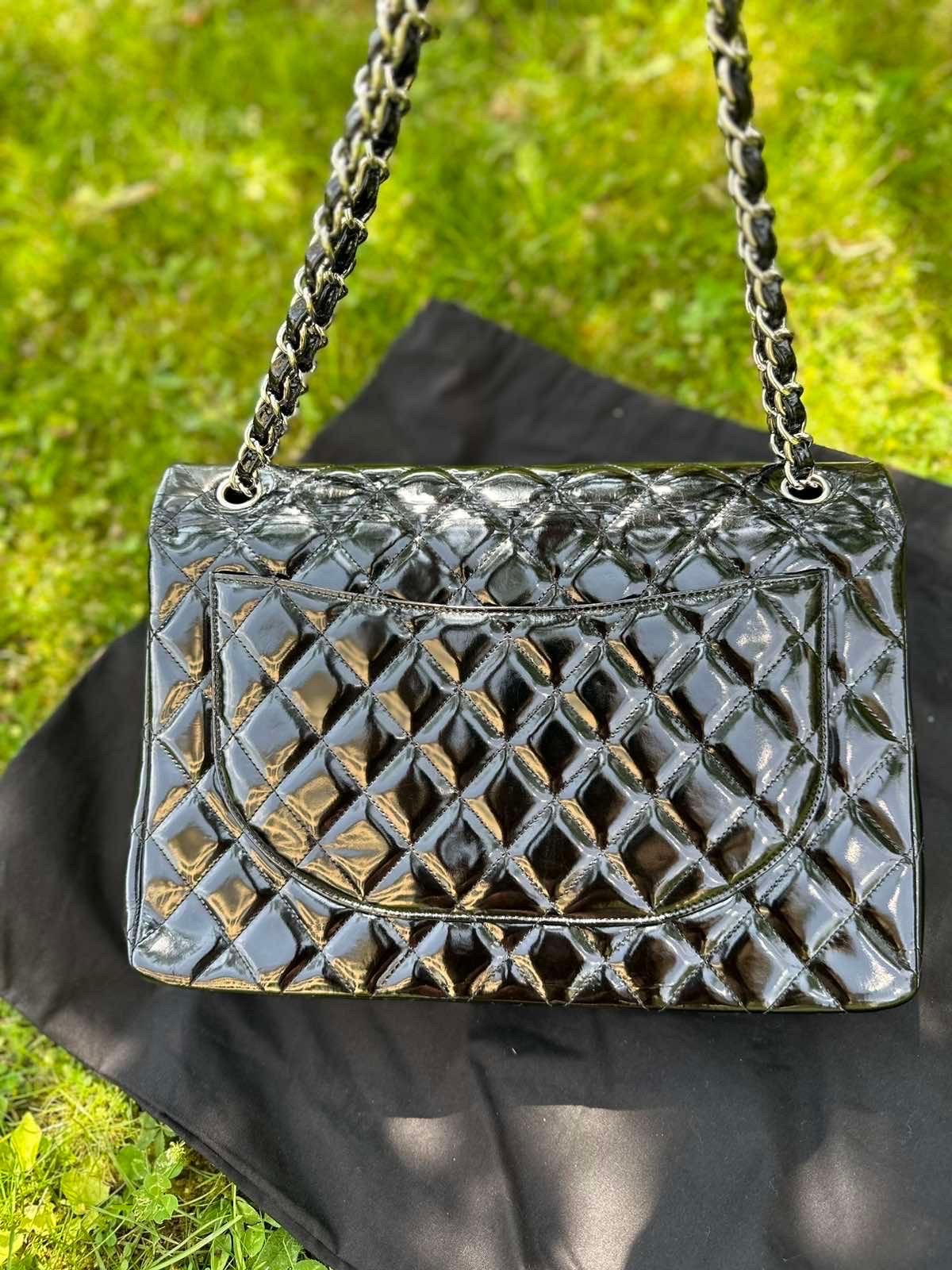 Chanel Jumbo Double Flap bag in black patent  leather with metallic details in silver.
This particular bag features quilted, glossy patent leather, and also features a silvertone turnlock CC closure and double flap top. The versatile leather strap