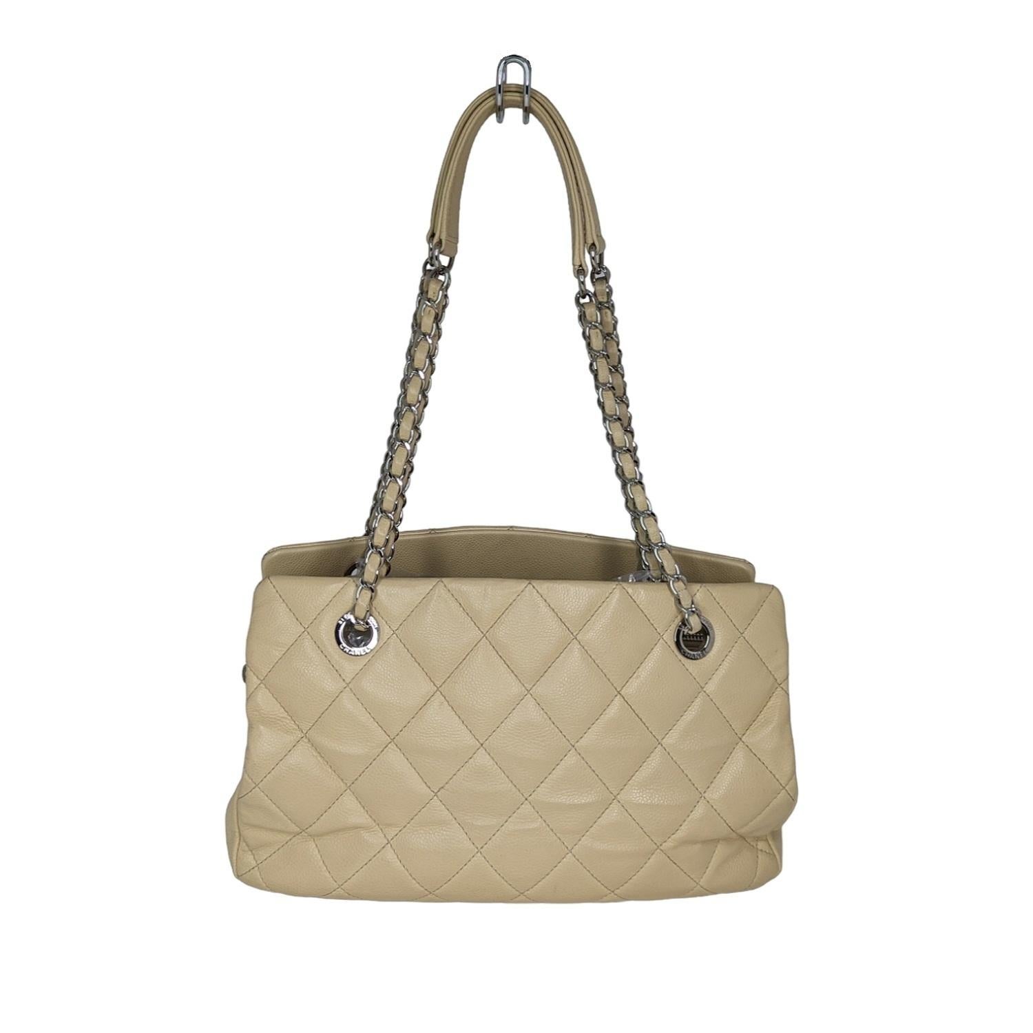 This Chanel Timeless Classic Caviar Quilted Tote is crafted from light beige quilted caviar leather. It features leather woven chain straps with leather shoulder pads, protective base studs, and silver-toned hardware. The interior is a camel-colored
