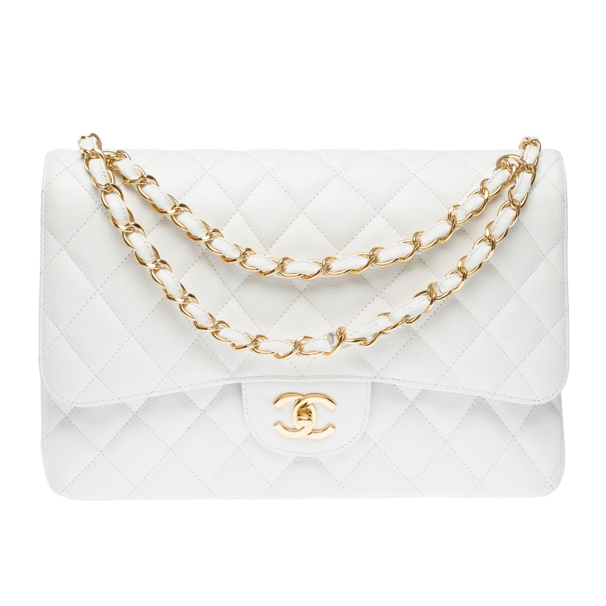 Majestuoso bolso Chanel Timeless Jumbo de doble solapa en piel de caviar blanca, adornos de metal dorado, asa de cadena en metal dorado entrelazado con piel blanca para llevar en la mano, al hombro o cruzado

Un bolsillo de parche en la parte