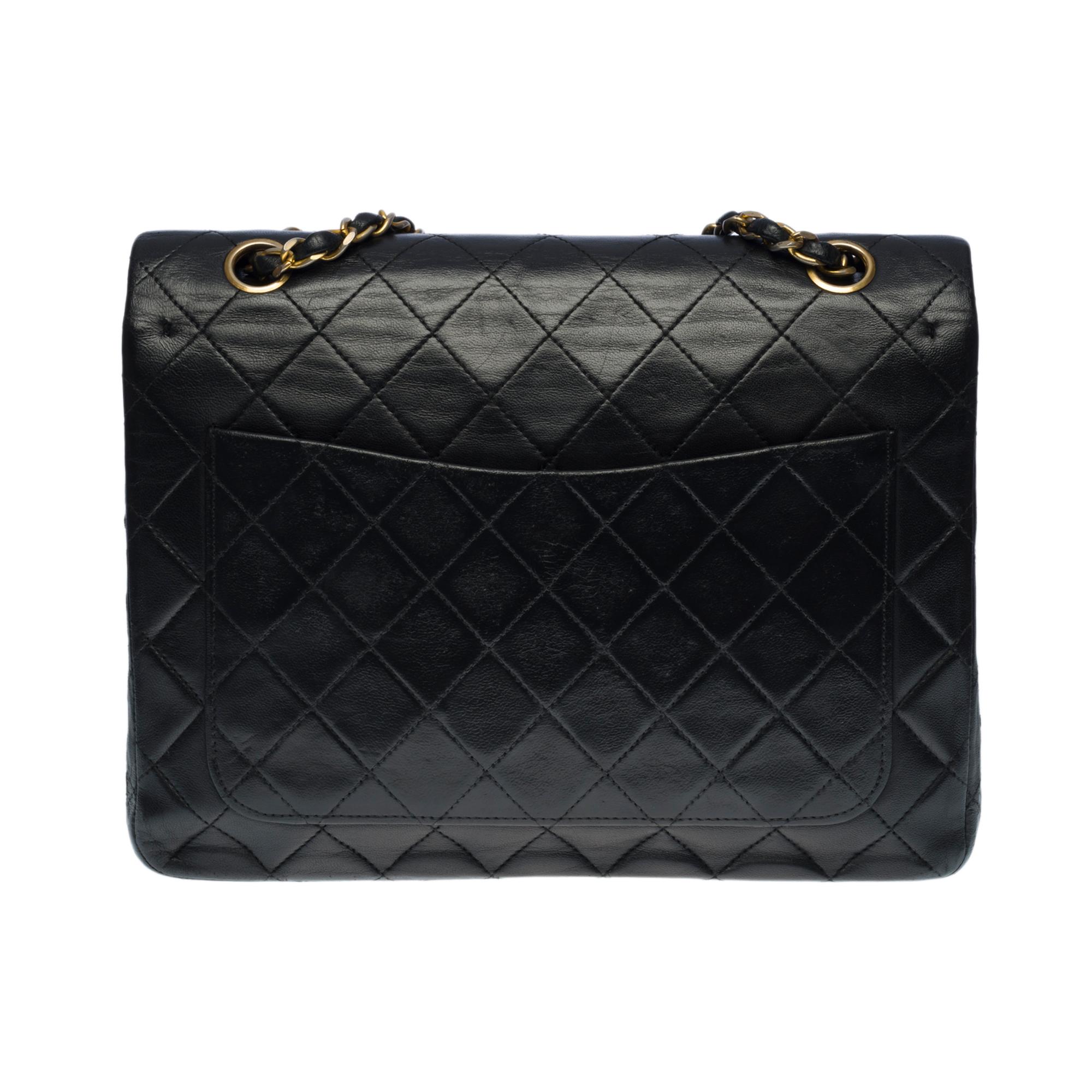 The coveted Chanel Timeless/Classique medium 25 cm bag with double flap in black quilted leather, hardware in gold metal, a chain strap in gold metal interlaced with black leather to be worn on the shoulder and across the body

Patch pocket on the