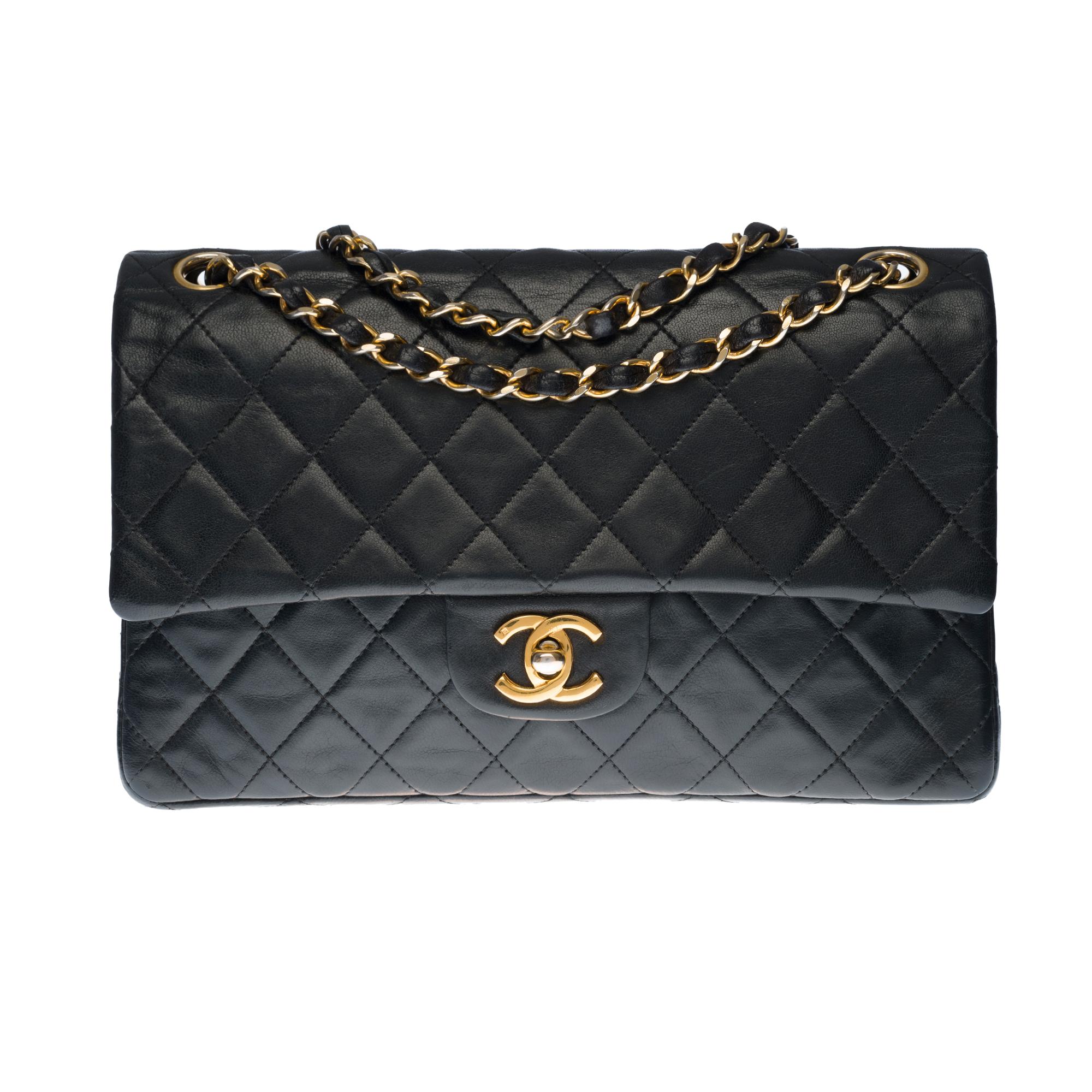Beautiful Chanel Timeless Medium 25cm handbag with double flap in black quilted lambskin leather, gold-tone metal hardware, a gold-tone metal chain handle interwoven with black leather allowing a hand or shoulder support.

Closure with gold metal