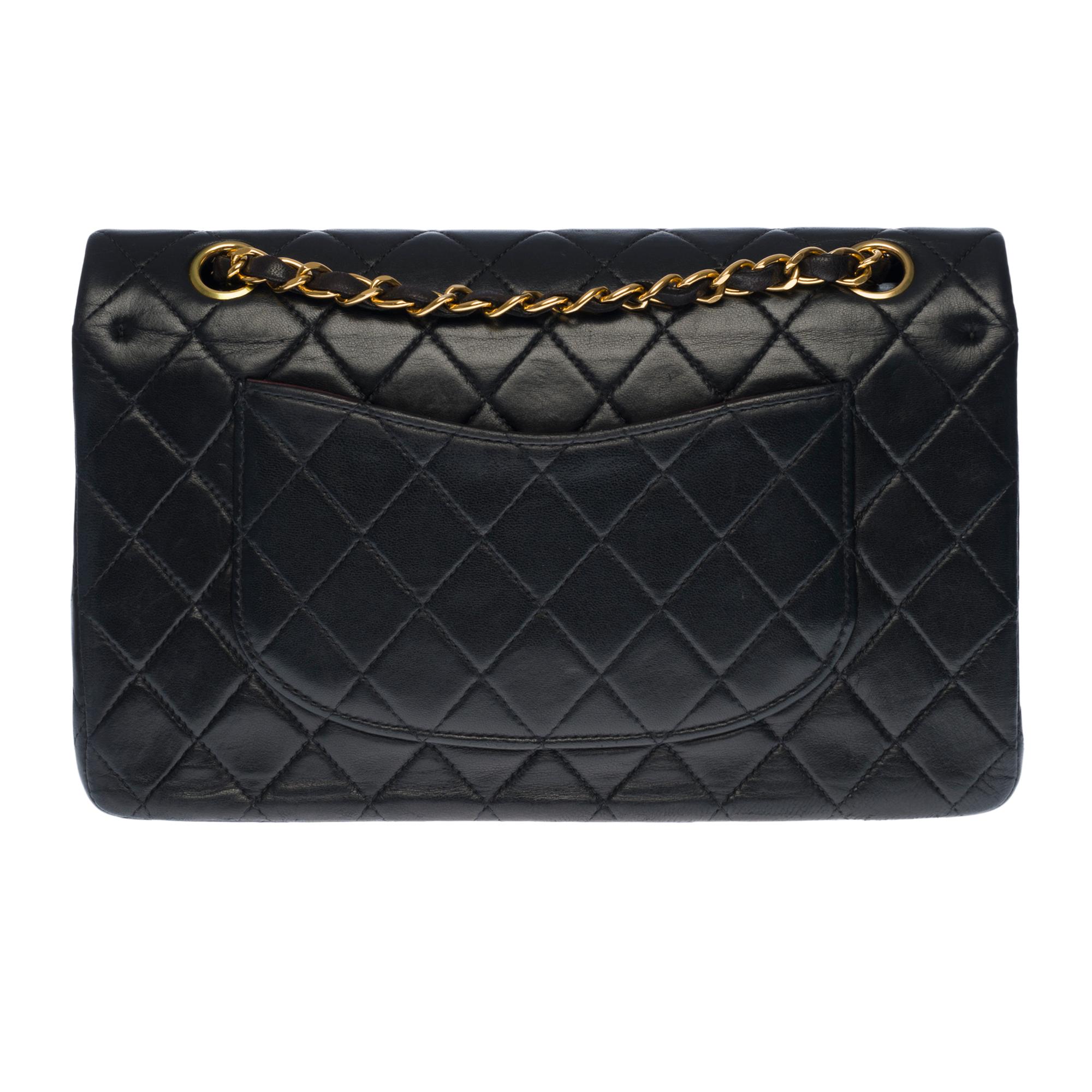 Beautiful Chanel Timeless Medium 25cm handbag with double flap in black quilted lambskin leather, gold-tone metal hardware, a gold-tone metal chain handle interwoven with black leather allowing a hand or shoulder support

Closure with gold metal
