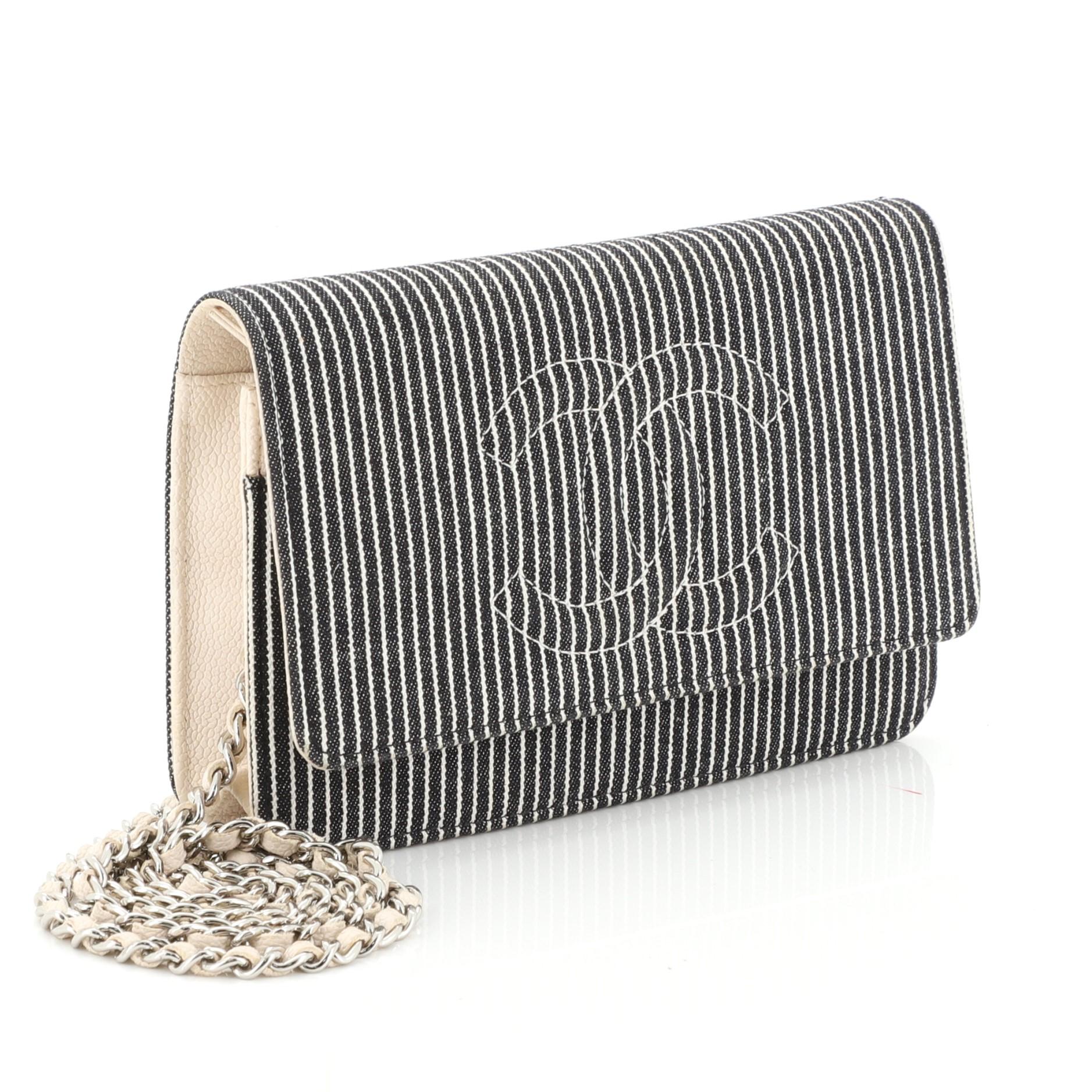 This Chanel Timeless Wallet on Chain Striped Denim, crafted in black striped denim, features woven-in leather chain strap, interlocking CC logo stitched on front and silver-tone hardware. Its snap button closure opens to a neutral fabric and leather