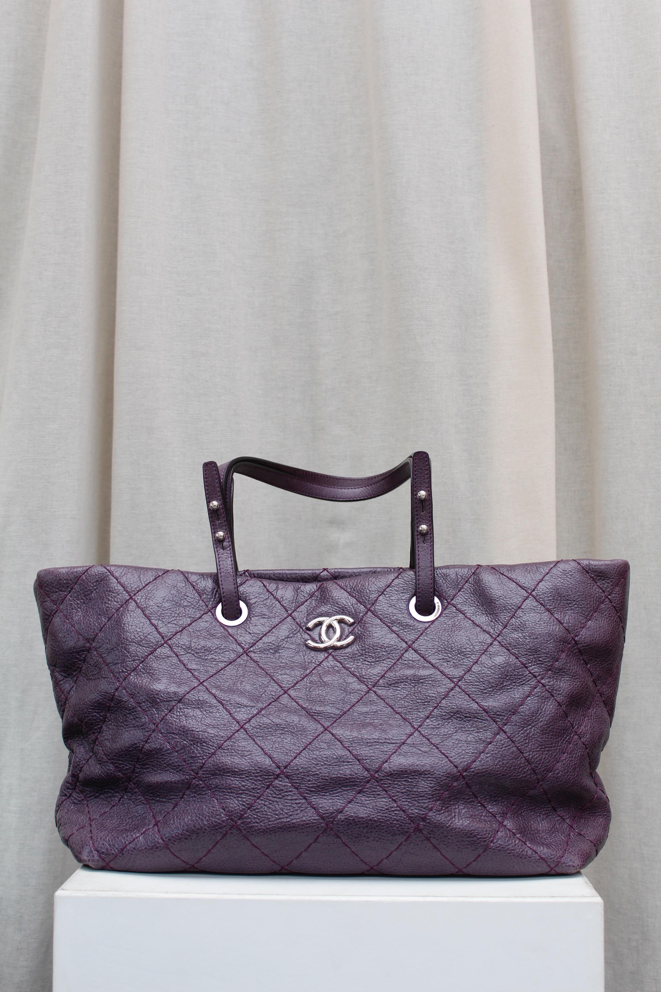 CHANEL (Made in Italy) Fabulous tote bag composed of over stitched eggplant color glazed leather. It can be carried by hand or over the shoulder, thanks to two adjustable leather handles.

It is decorated on one side with a silver plated CC logo.