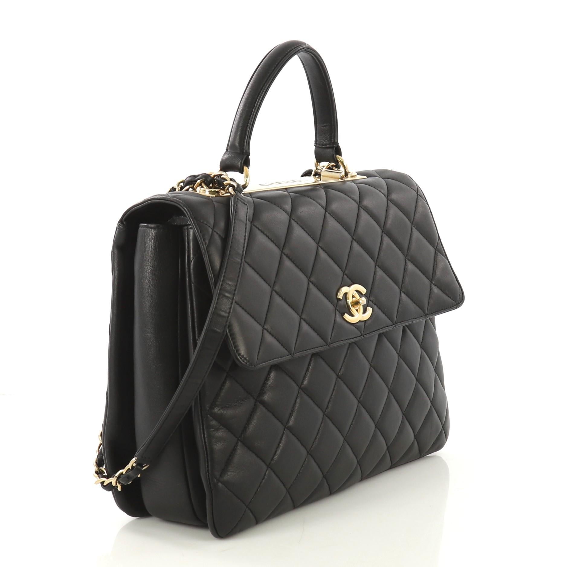 This Chanel Trendy CC Top Handle Bag Quilted Lambskin Large, crafted from black quilted lambskin, features a leather top handle, woven-in leather chain strap with leather pad, and gold-tone hardware. Its turn-lock closure opens to a burgundy leather