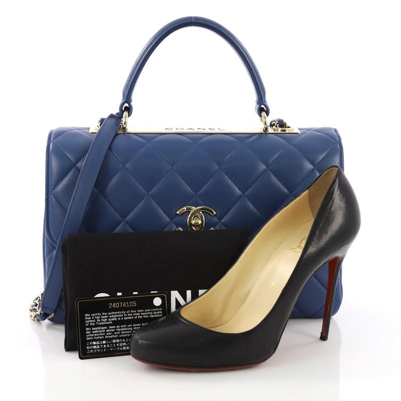 This Chanel Trendy CC Top Handle Bag Quilted Lambskin Medium, crafted from blue quilted lambskin, features a flat leather top handle, woven-in leather chain strap with leather pad, and gold-tone hardware. Its turn-lock closure opens to a burgundy