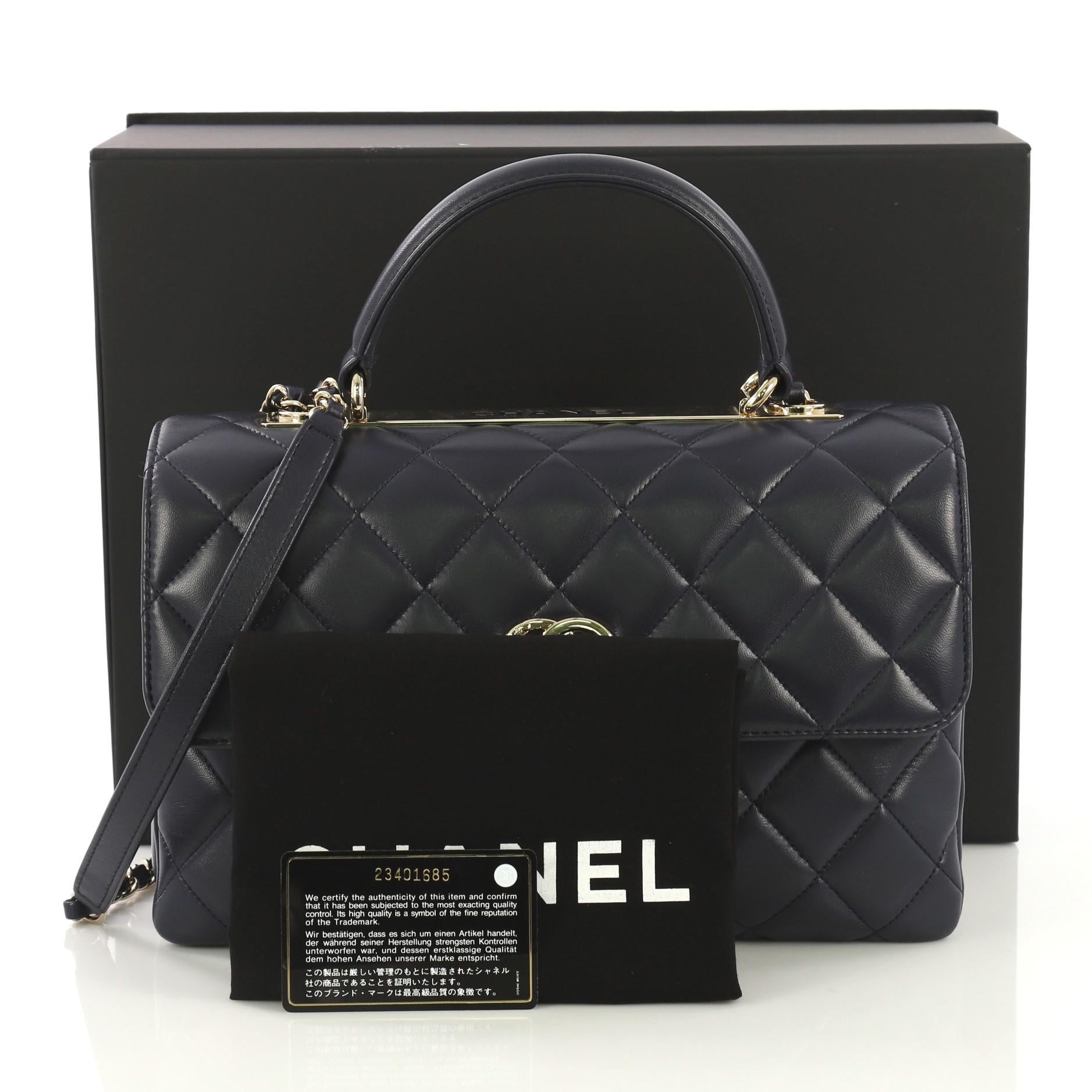 This Chanel Trendy CC Top Handle Bag Quilted Lambskin Medium, crafted from dark blue quilted lambskin, features a leather top handle, woven-in leather chain strap with leather pad, and gold-tone hardware. Its turn-lock closure opens to a burgundy