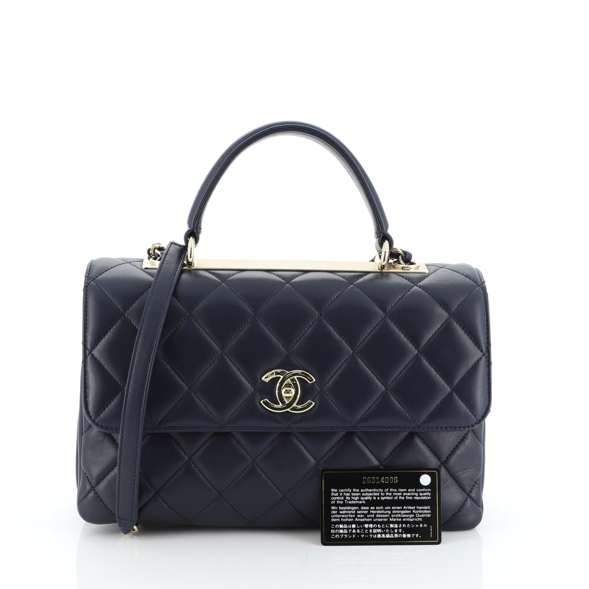 This Chanel Trendy CC Top Handle Bag Quilted Lambskin Medium, crafted from blue quilted lambskin, features a leather top handle, woven-in leather chain strap with leather pad, and gold-tone hardware. Its turn-lock closure opens to a blue leather